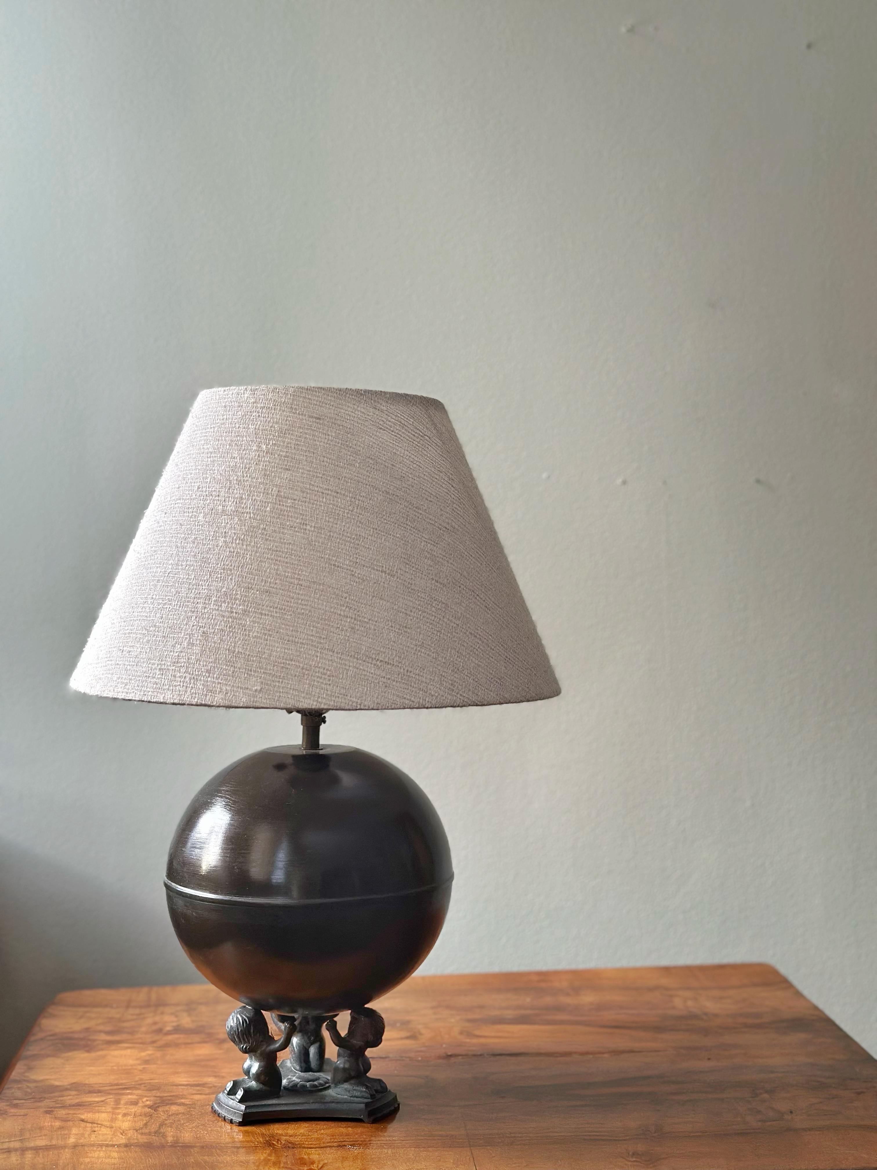 Elegante lampe de table suédoise en bronze Art déco avec des pieds distinctifs en bronze patiné. La base ronde en bronze est peinte en brun foncé semi-brillant.
Cette lampe a été conçue par NILSSON & JOHANSSON pour Äkta Brons Svensk Vara dans les