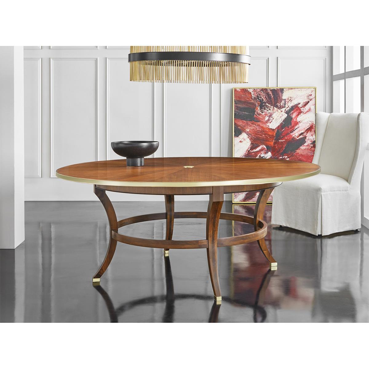 An Art Deco round dining table. Warm brown walnut veneers with a rayed inlaid top, a solid brass central applique and brass trim molding. Raised on four sabre form legs with a round stretcher and brass feet.

Dimensions: 72