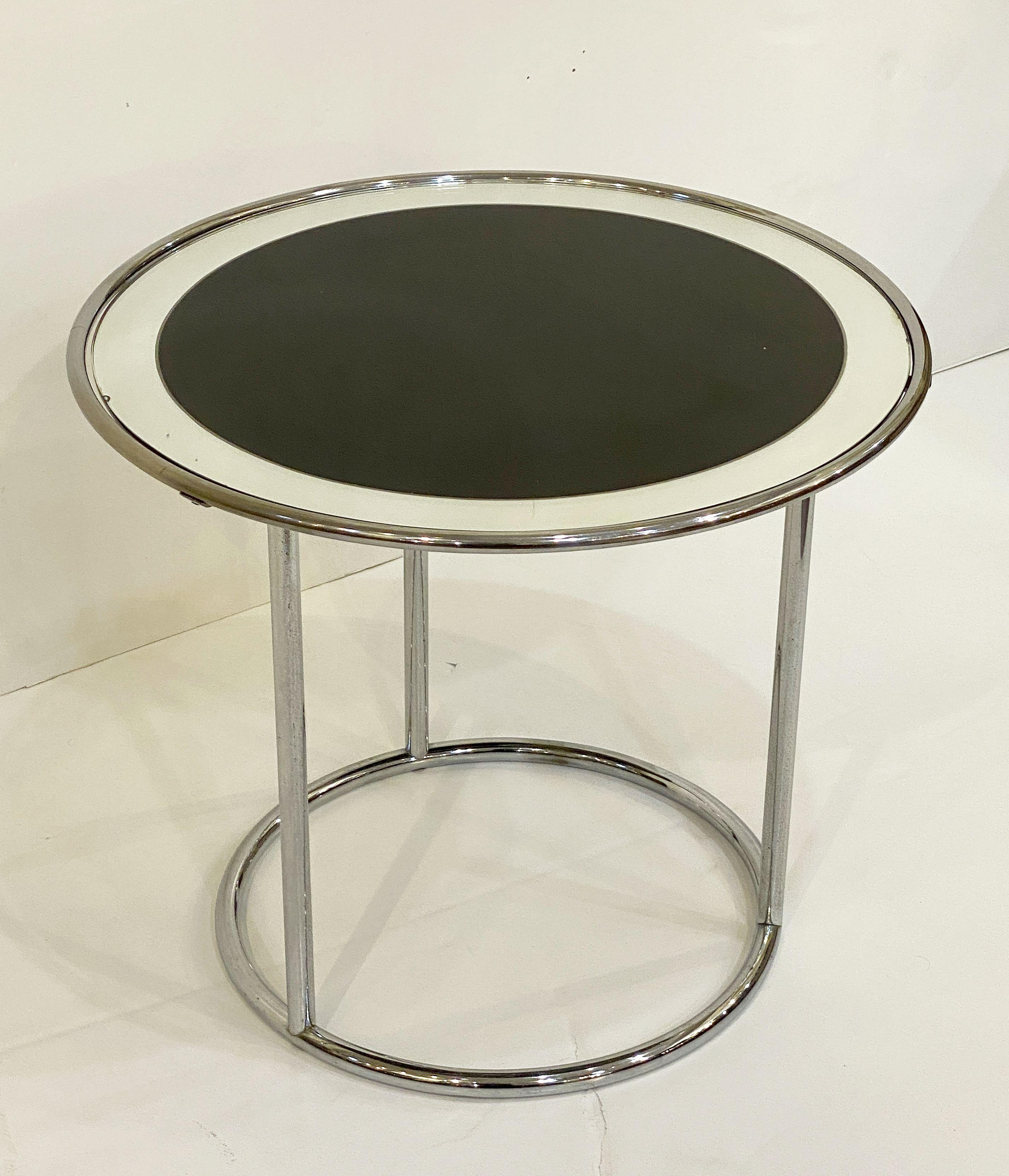 A fine English round or circular side table with a frame of chromed tubular steel from the Art Deco era, featuring a top circle tier of mirrored glass, set upon three tubular column supports. 

With maker's mark on base: J.M. Doughty & Sons, Ltd -
