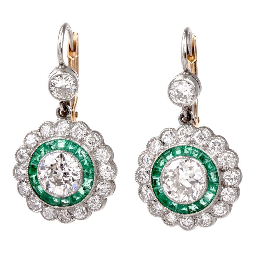 These captivating estate earrings with a pair of prominent round old European-cut diamonds and trapezoid-cut translucent emeralds are crafted in solid platinum weighing 5.7 grams. They incorporate a geometrically inspired orbicular plaque measuring