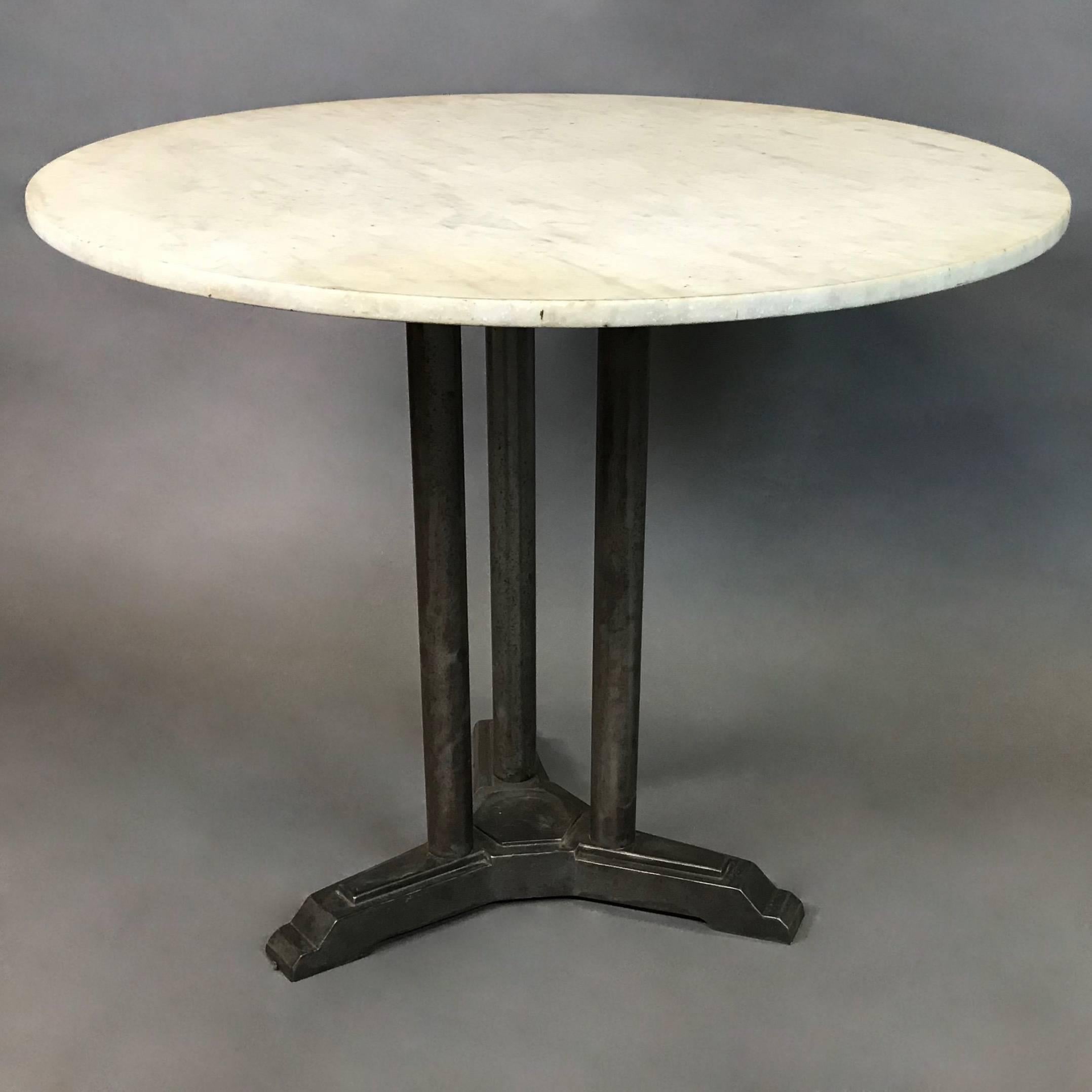 Art Deco, café, bistro, dining table features a round white marble top with stepped, cast iron, three stem pedestal base.