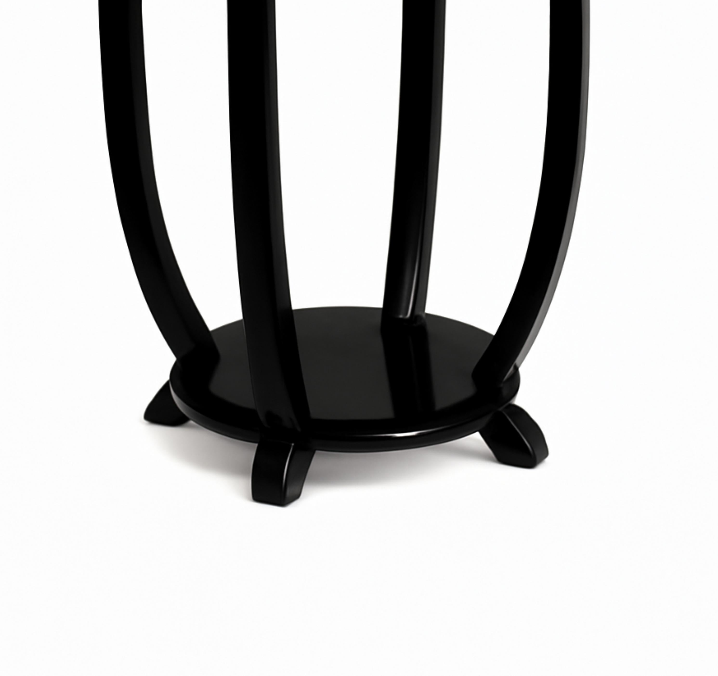 Questo tavolino Art Déco in noce e lacca nera della Francia degli anni Venti è stato realizzato con una struttura rotonda a due livelli, con quattro gambe graziosamente curve collegate a una base circolare.

Vero e proprio pezzo forte, questo tavolo