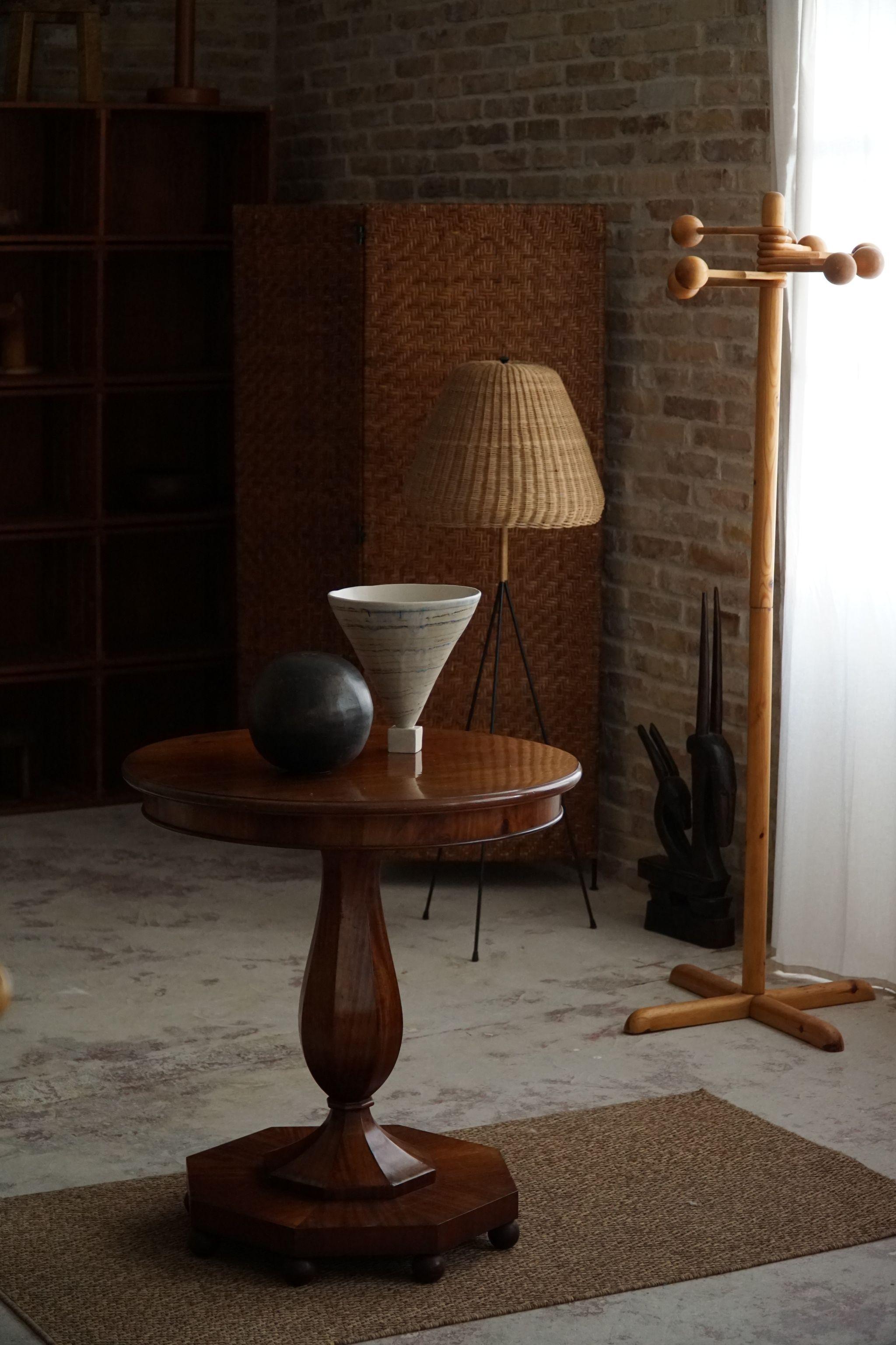 Dieser luxuriöse runde Sockel- und Beistelltisch ist ein beeindruckendes Zeugnis der Handwerkskunst eines dänischen Tischlers in der glamourösen Ära der 1940er Jahre. Dieses aus Nussbaumholz gefertigte Möbelstück vereint Form und Funktion und