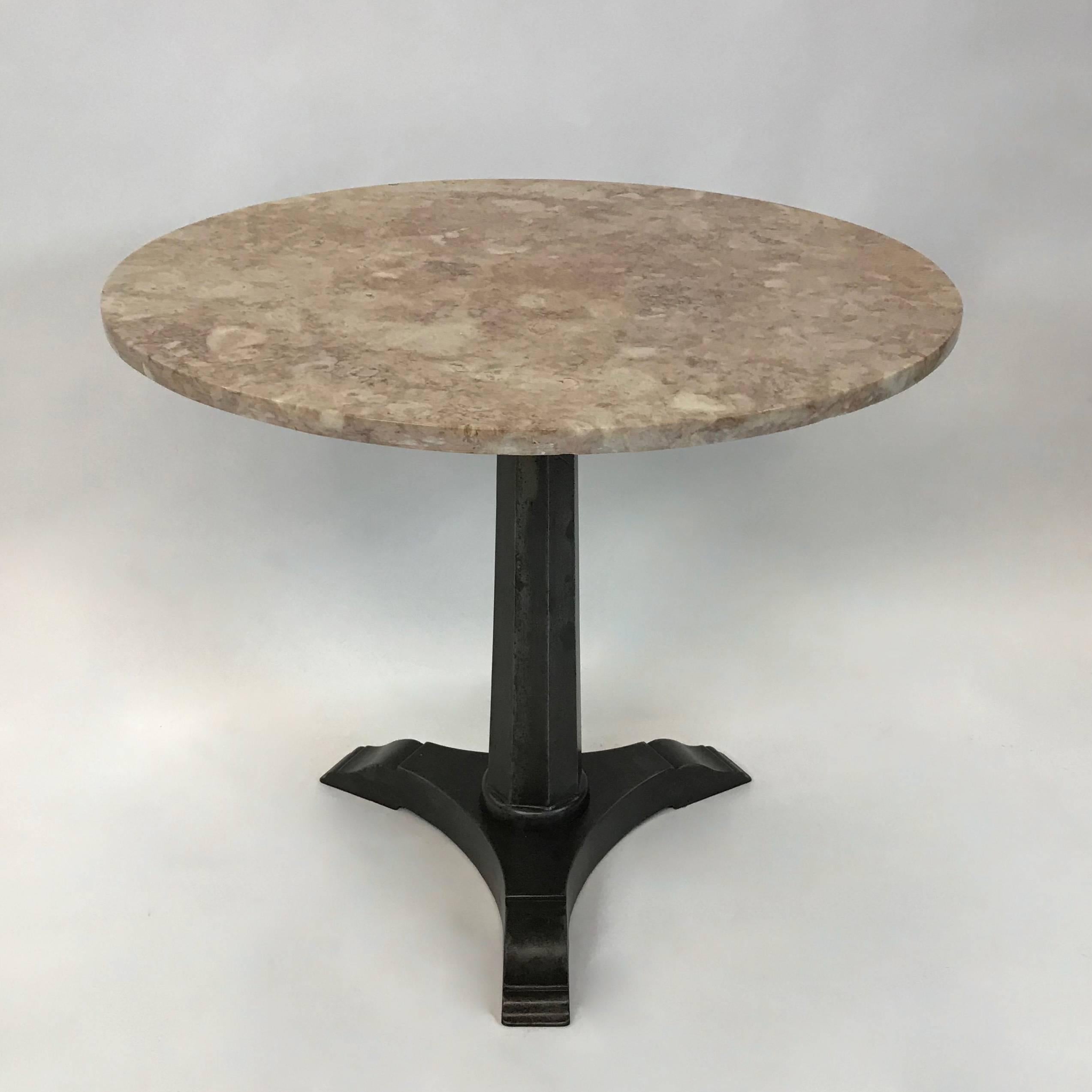 Cafe, bistro, dining table features a 36 inch round, blush pink marble top with Art Deco, cast iron, skyscraper pedestal base.