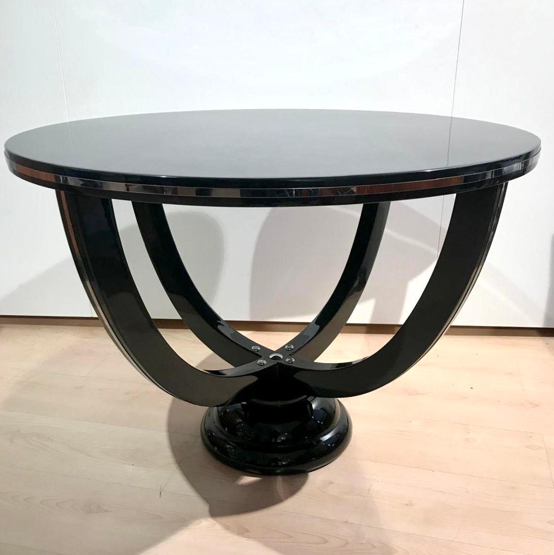 Grande table ronde d'appoint, de canapé ou de café Art Déco, France, vers 1930.
Laque piano noire, polie haute brillance. Quatre pieds incurvés sur une base ronde.
Garnitures en acier inoxydable poli sur l'extérieur des deux pieds et sur le pourtour