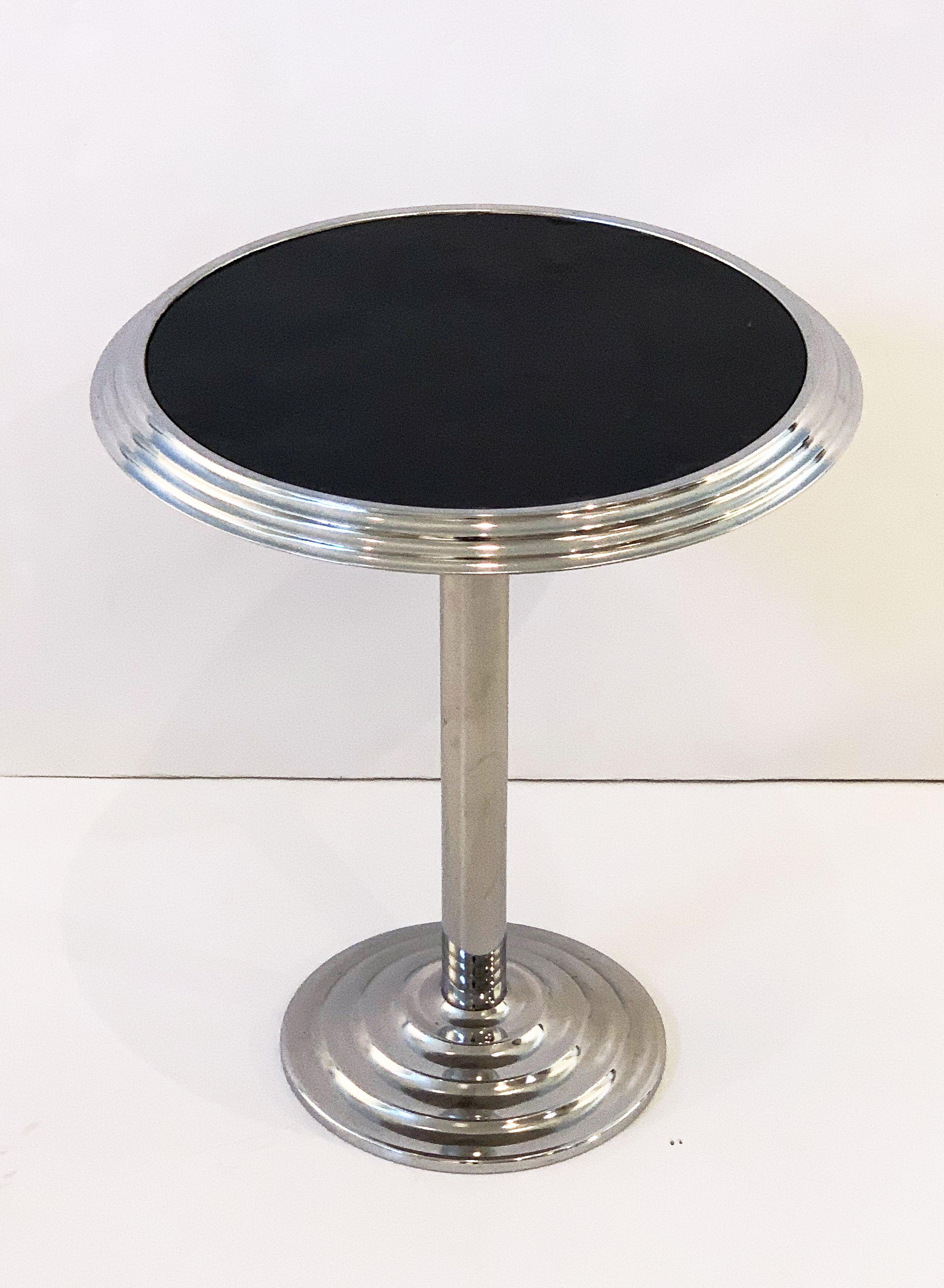 A fine French round bistro or pub table of chromed steel from the Art Deco period, featuring a circular graduated top with black center overlay of man-made materials, mounted to a column pedestal with graduated concentric base.