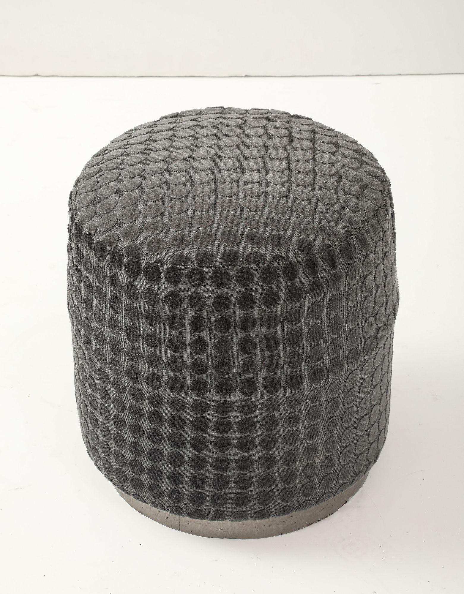 Esta otomana redonda Art Decó vintage presenta un tapizado en relieve con motivos circulares en tela gris oscura, combinado con una elegante base metálica para crear contraste. La silueta cilíndrica y la sencillez arquitectónica ofrecen