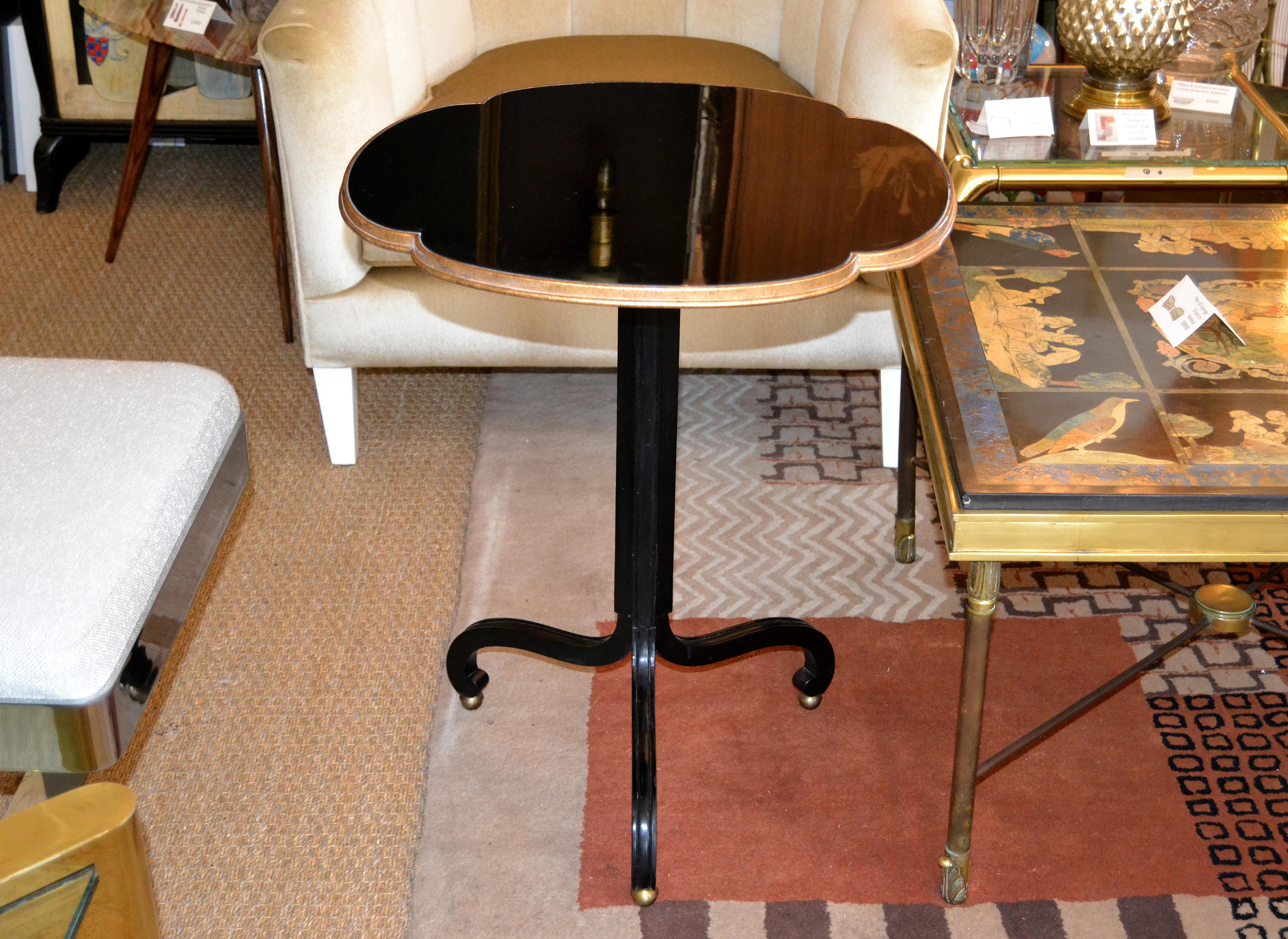 Art Deco round three legged mahogany side table with a black laminate top by baker.
The sculptural legs have nice round brass ball feet to it.
The baker metal tag is attached under the top as well as numbered.
Can be used as a side or as a