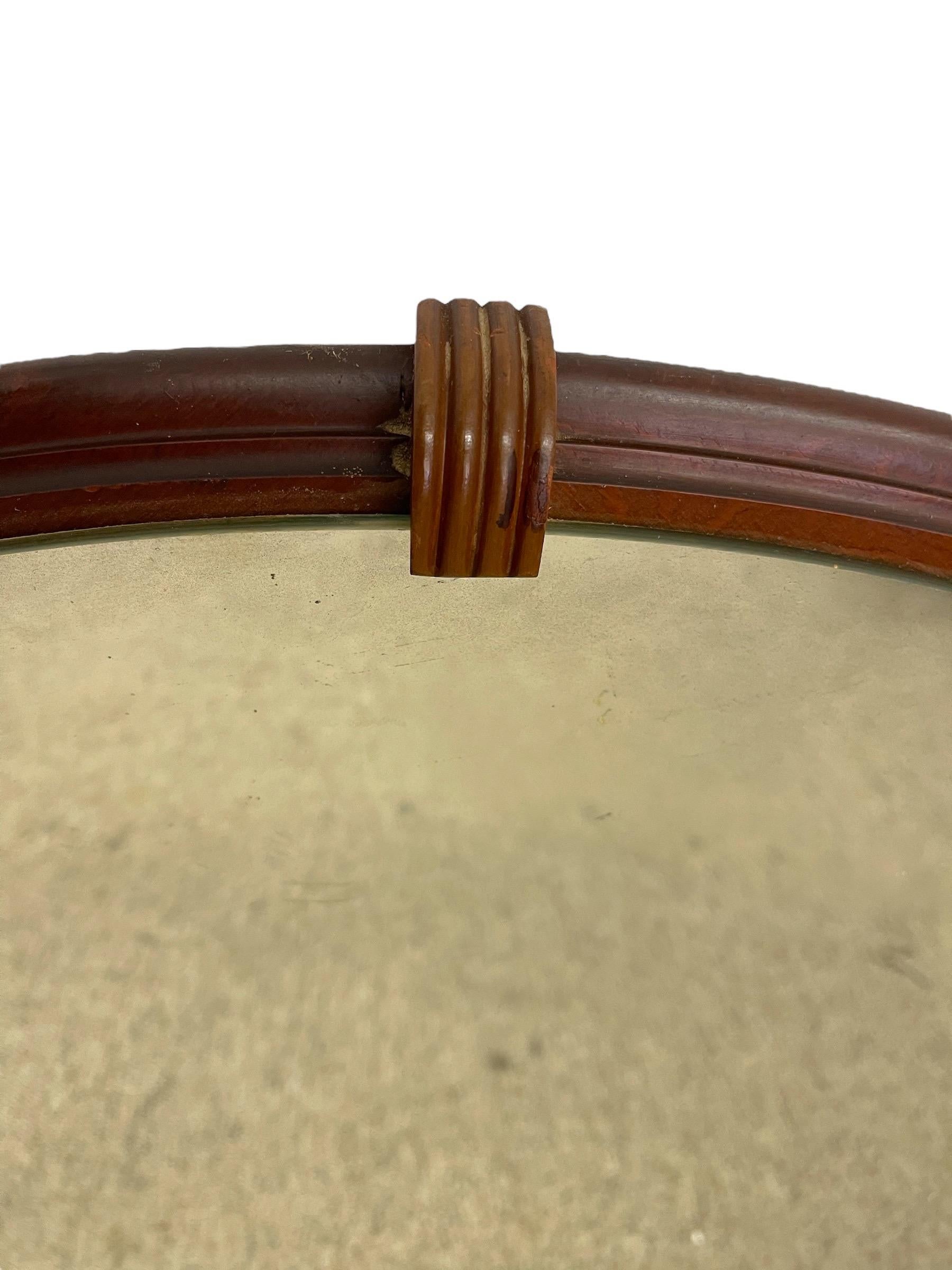An Art Deco round wall mirror featuring a warm walnut-toned wooden frame secured with decorative ribbed wood clips at three points. This classic circular design reflects the streamlined geometry and craftsmanship of the Art Deco era, offering both