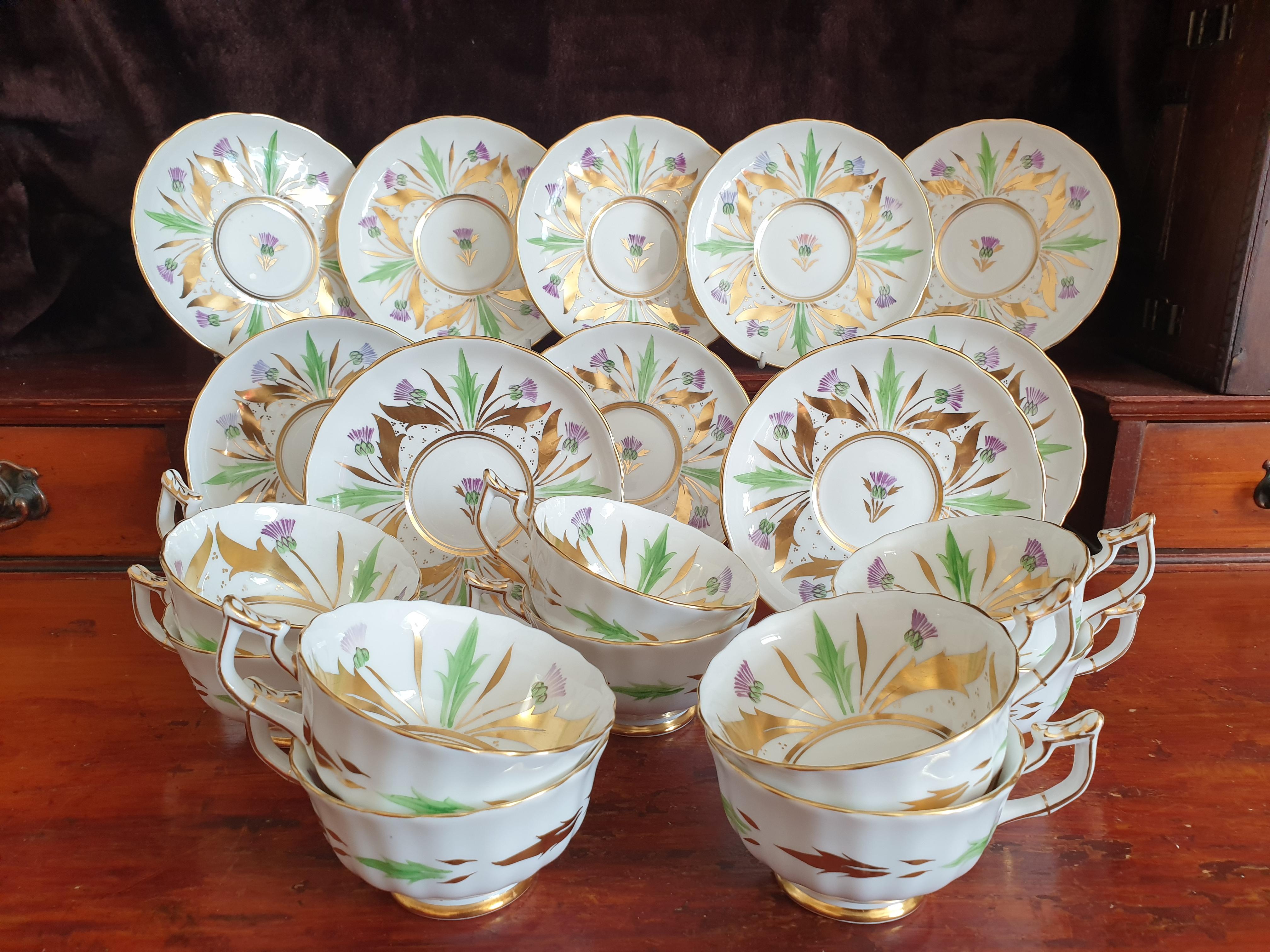 Royal Chelsea Art Deco 10 cups and matching saucers tea service. All handpainted with richly decorated with gilt leaves with further floral decorations in pastel green and purple inside the walls of the cups, saucers and to the centre of