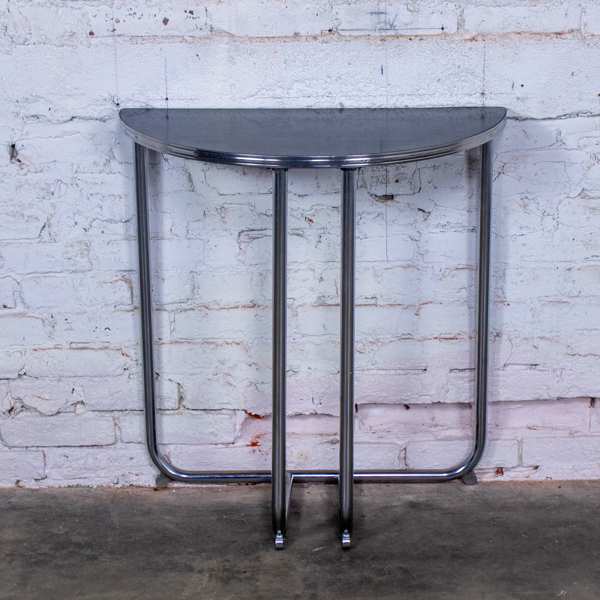 Handsome vintage Art Deco Streamline Moderne demilune console table composed of a chrome tube frame w/a time faded black early laminate top by Royalchrome. Beautiful condition, keeping in mind that this is vintage and not new so will have signs of