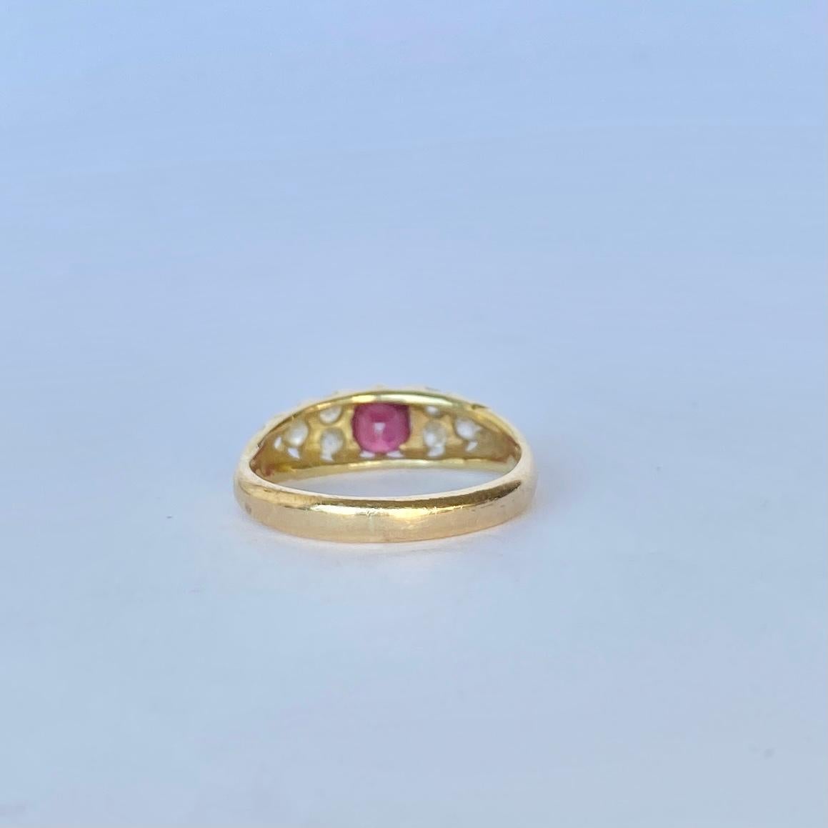 This stunning band holds a cherry red ruby at the centre measuring 45pts and a trio of diamonds either side. The diamonds total 30pts. The ring is modelled in 18carat gold and has decorative cut out shoulders. 

Ring Size: L 1/2 or 6 
Band Width: