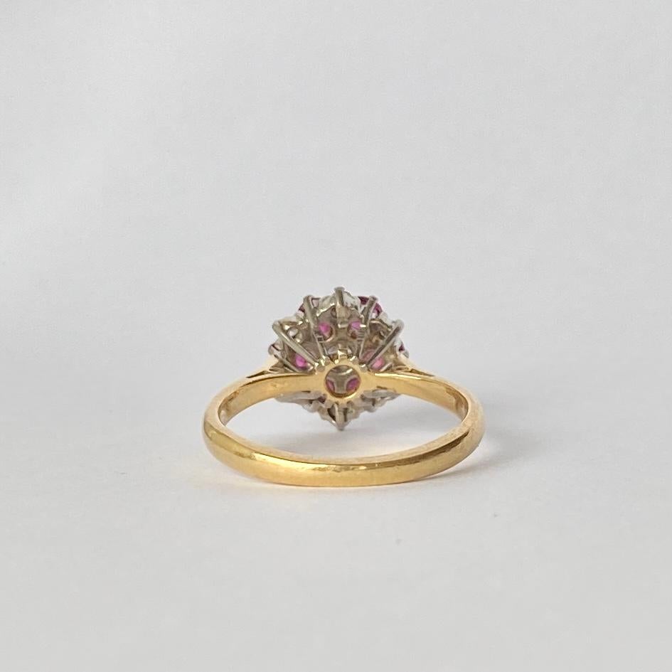 This bright ruby and diamond cluster is modelled in 18carat gold and the stones are set in platinum. The rubies total 90pts and the diamonds around it total 12pts and a 15pt diamond at the centre. 

Ring Size: L or 5 3/4
Cluster Dimensions: