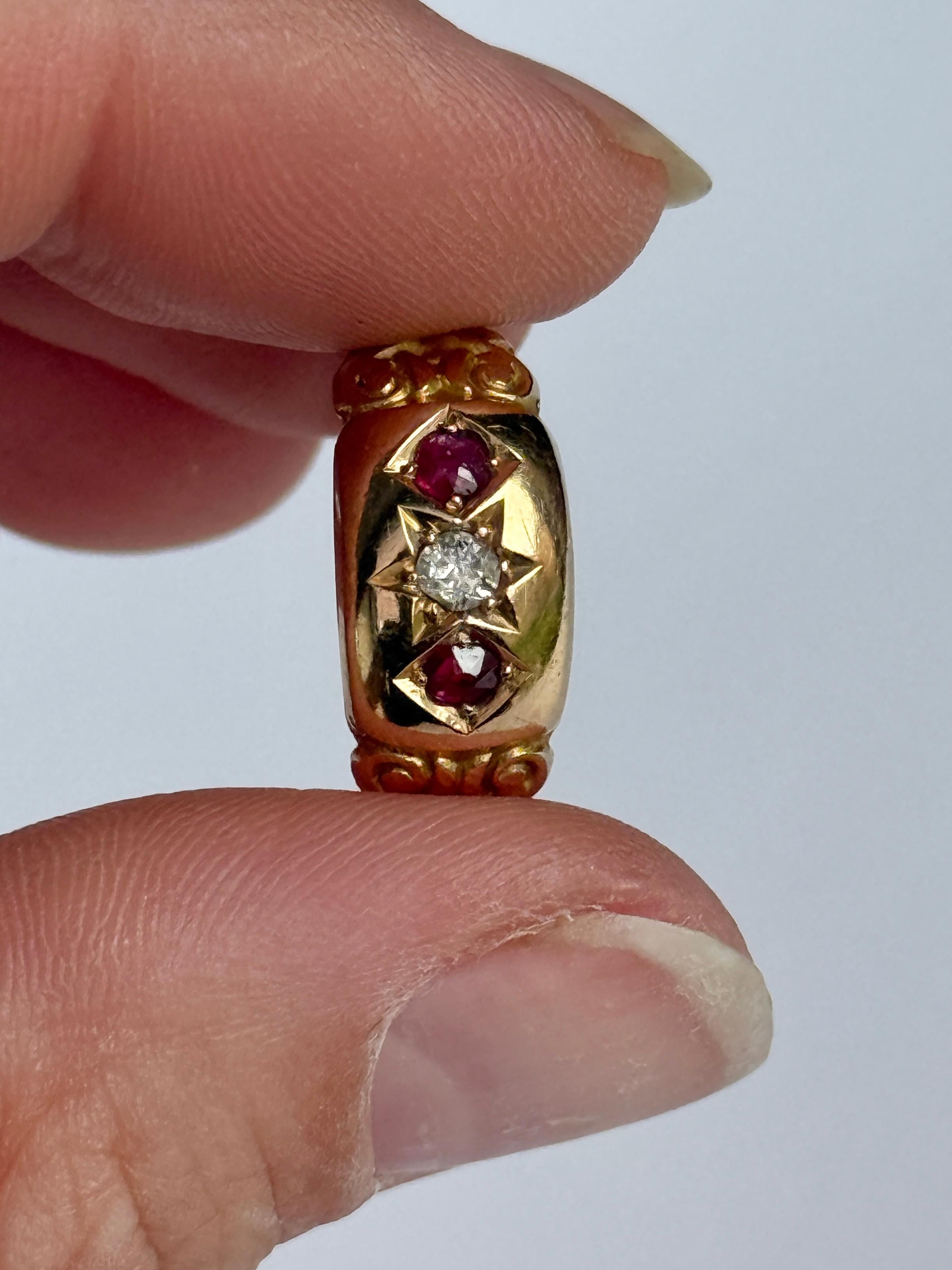 The central diamond in this glossy 18ct gold band measures 10pts. The rubies that sit either side of this stone measure 8pts each. Hallmarked Chester 1916.

Ring Size: O or 7 1/4 
Band Width: 8mm 

Weight: 3.2g 