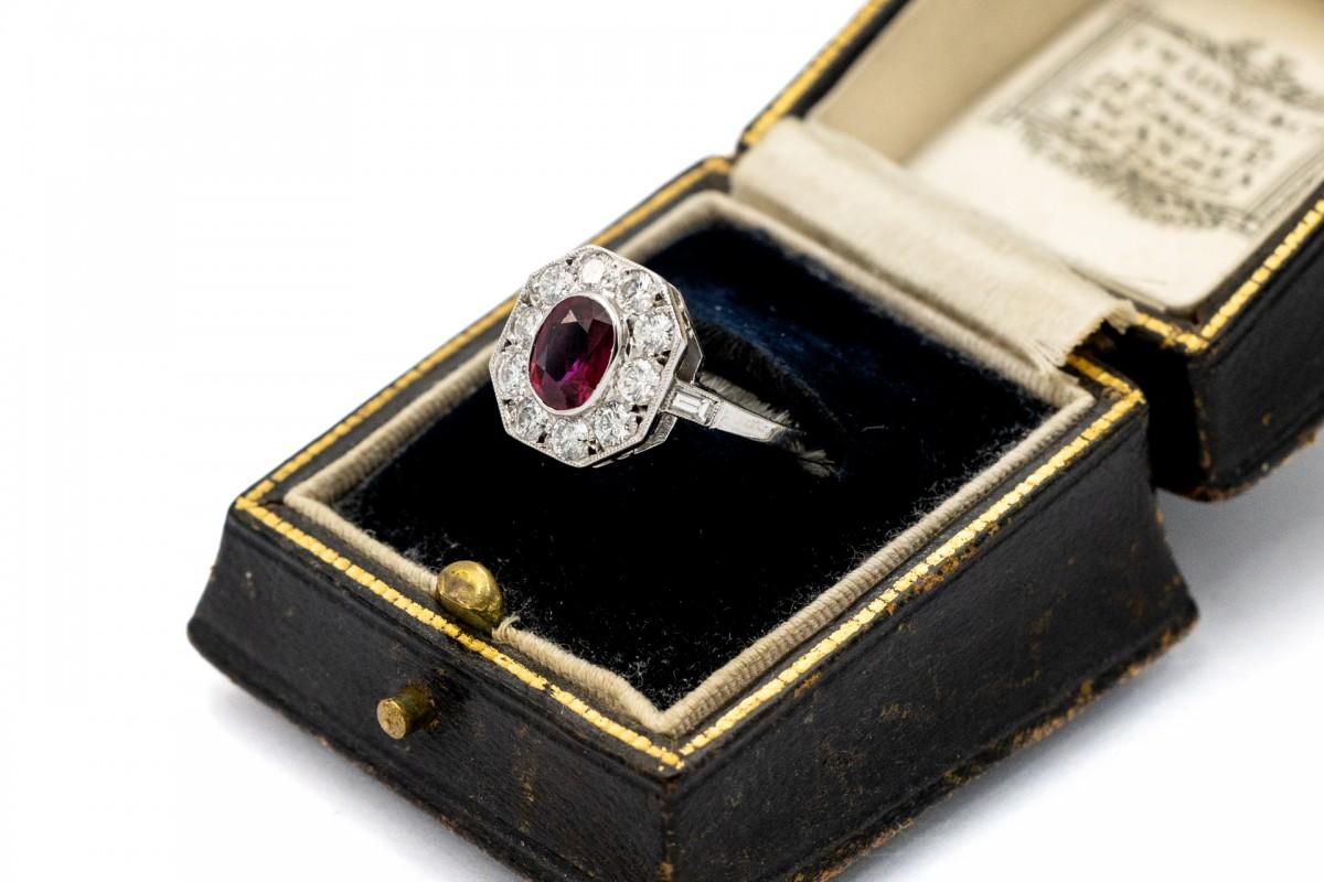 Anello in oro bianco con rubino, brillanti e diamanti. Questo affascinante anello è una combinazione unica di classicità ed eleganza.

Un rubino ovale dal colore rosso vivo e dal peso di 1,10 ct. L'anello è decorato con 10 diamanti taglio brillante
