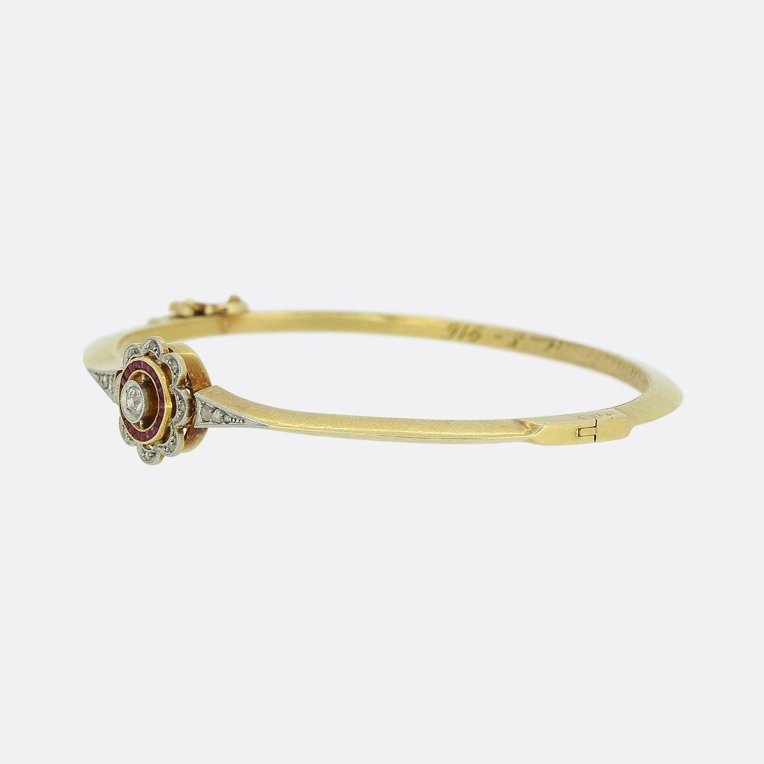 This is a truly wonderful 18ct yellow gold ruby and diamond hinge bangle from the Victorian era. The bangle features a central old cut diamond which is surrounded by a cluster of calibre cut rubies and then a further border of eight rose cut