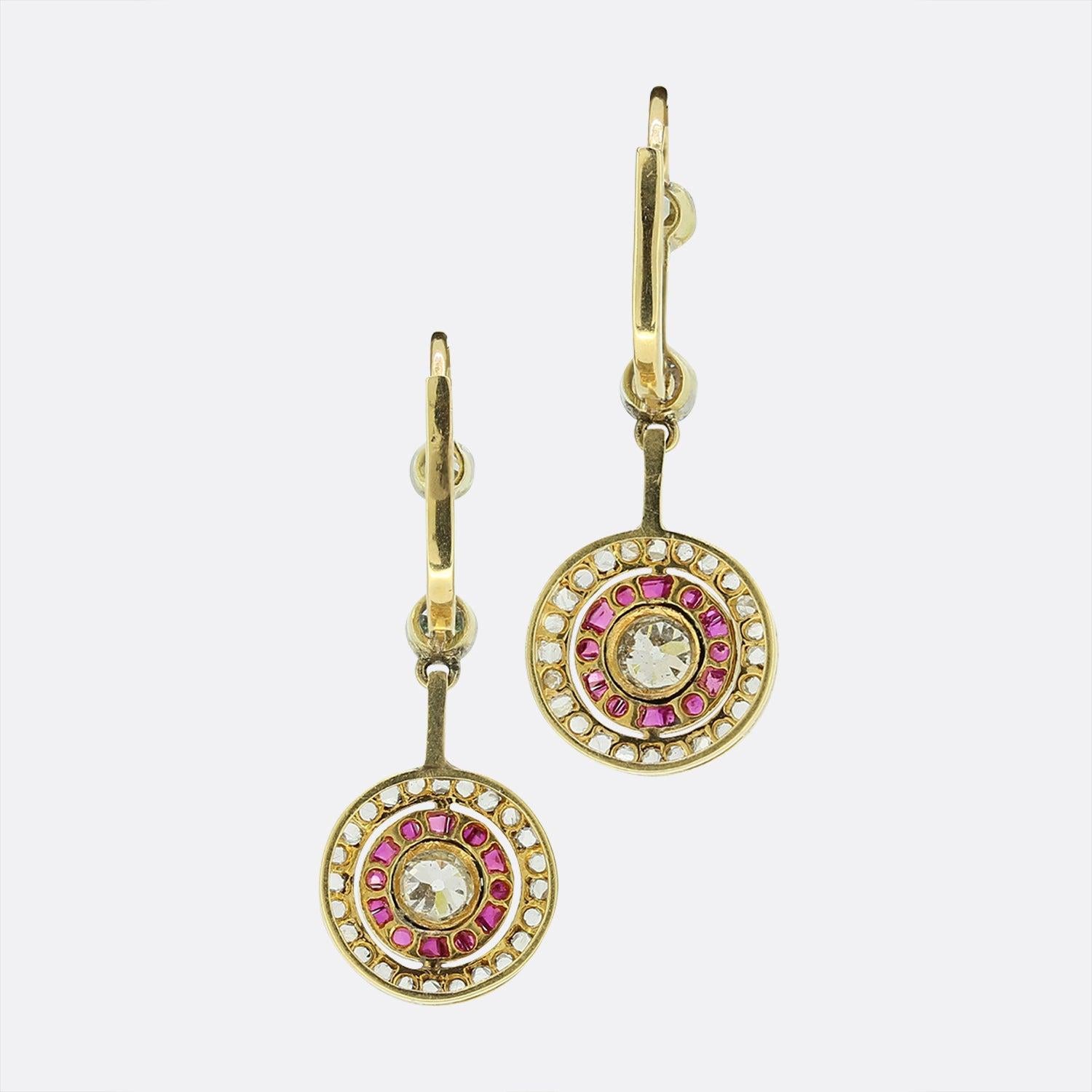 Ecco uno splendido paio di orecchini Art Deco con rubini e diamanti. Ogni pezzo presenta un singolo diamante antico circondato da rubini calibrati e da un ulteriore strato di diamanti taglio rosa. Queste pietre sono state incastonate con dettagli a
