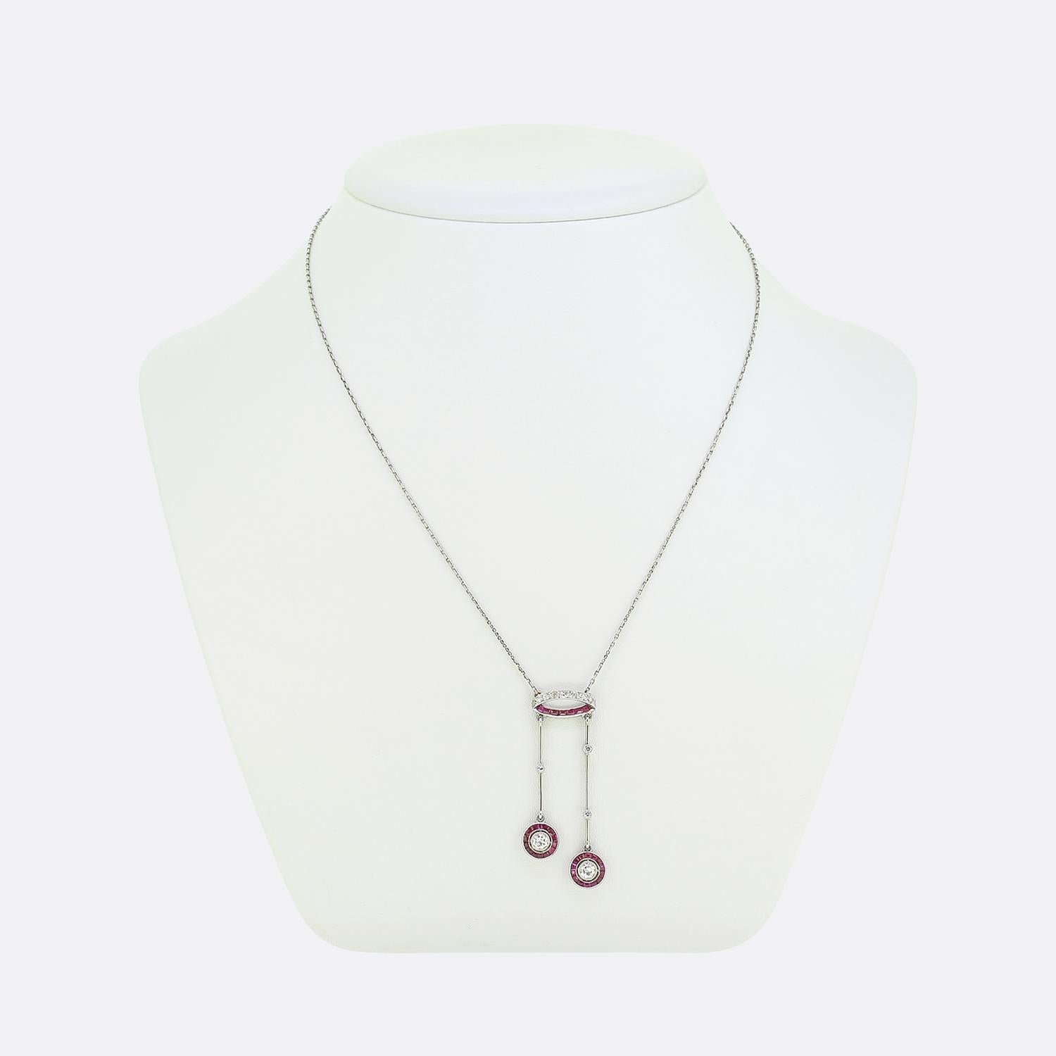 Hier haben wir ein exquisites Negligé-Halsband, das die Eleganz des Art Deco-Designs zeigt. Der aus Platin gefertigte Anhänger ist mit einer rubin- und diamantbesetzten Schlaufe versehen, an der zwei diamantbesetzte Messerleisten angebracht sind,