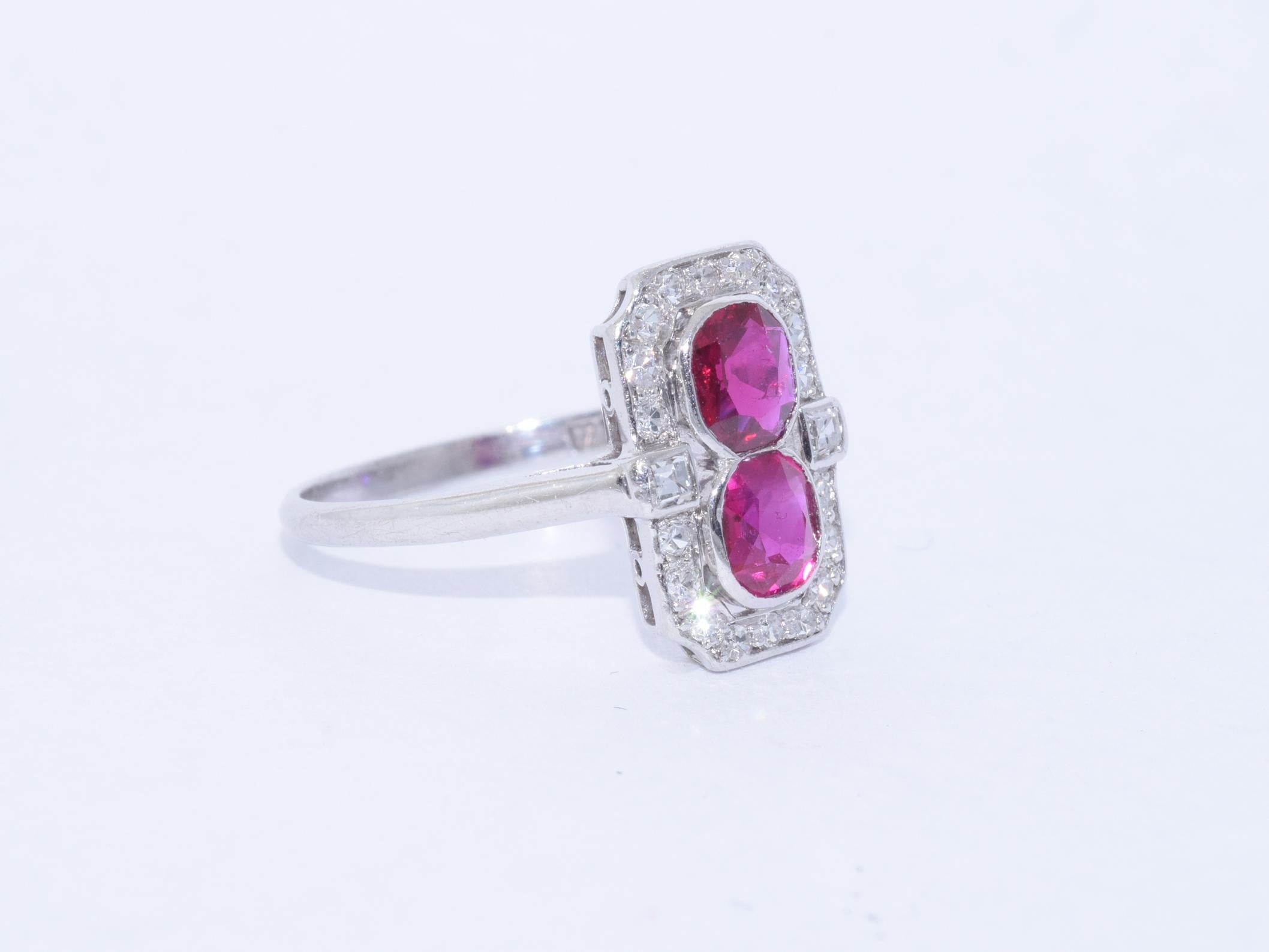 Twin cushion rubies totaling approximately 1 carat are accented with single cut and square diamonds totaling approximately 0.50 carat mounted in platinum. The top of the ring measures approximately 0.54 x 0.39 inches and is currently a size 6.5.