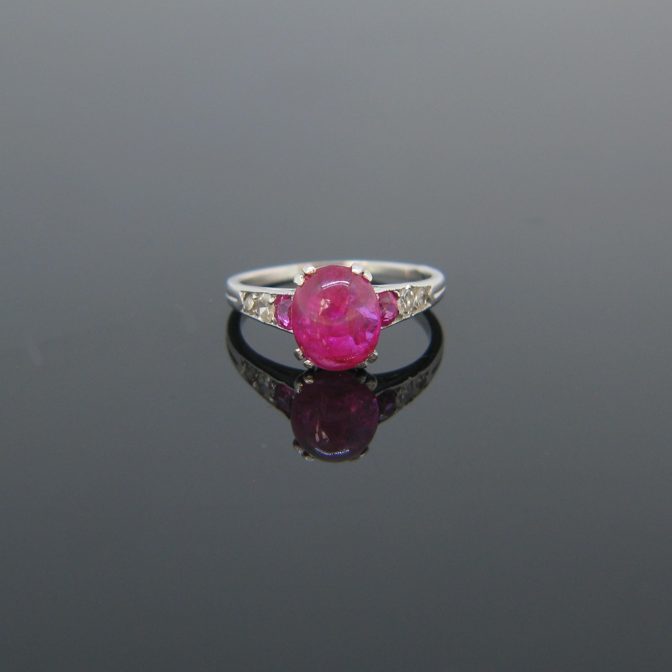 This beautiful Art Deco era is fully made in platinum. It is set with a cabochon ruby (no indications of heating) and is adorned on the sides with 4 single cut diamonds and two additional rubies. The ruby has a vibrant pink colour. It is a truly
