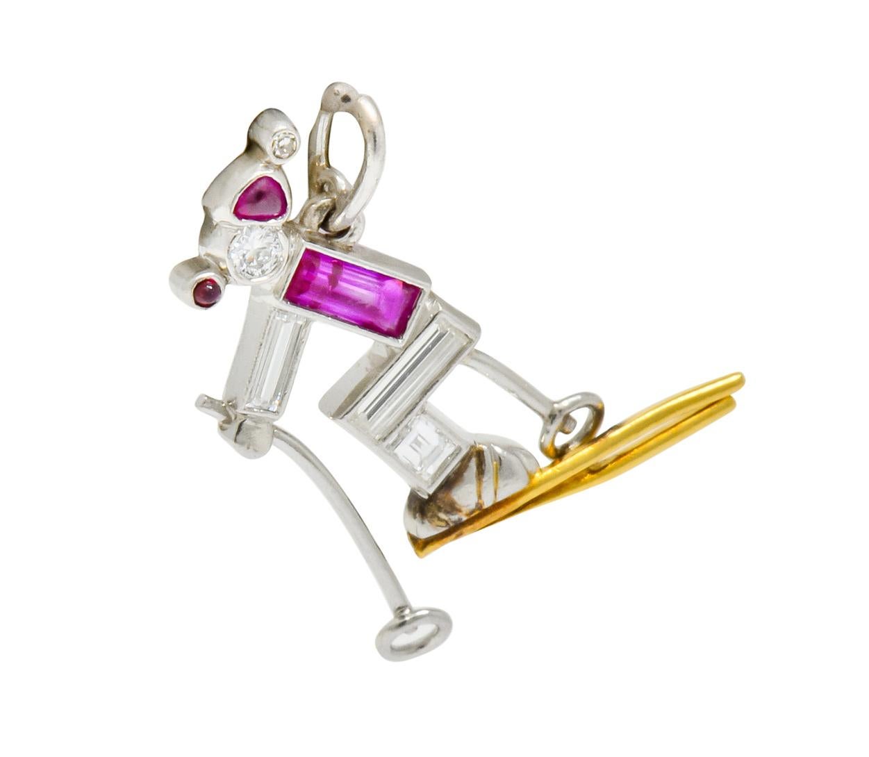 Designed as a crouched cross country skier grasping two poles while gliding on two polished gold skis

Stylized geometric body is comprised of baguette cut diamonds and ruby while head is a round brilliant cut diamond

Completed by a small whimsical