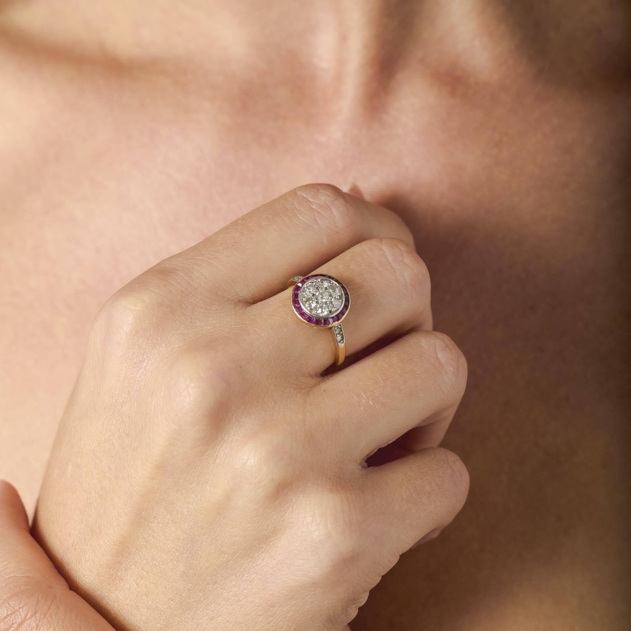 A dazzling expression of Art Deco geometry and color, this 1930s target ring showcases a brilliant arrangement of old European and rose cut diamonds encircled by a vivid halo of French cut rubies. The precise symmetry and clean lines capture the