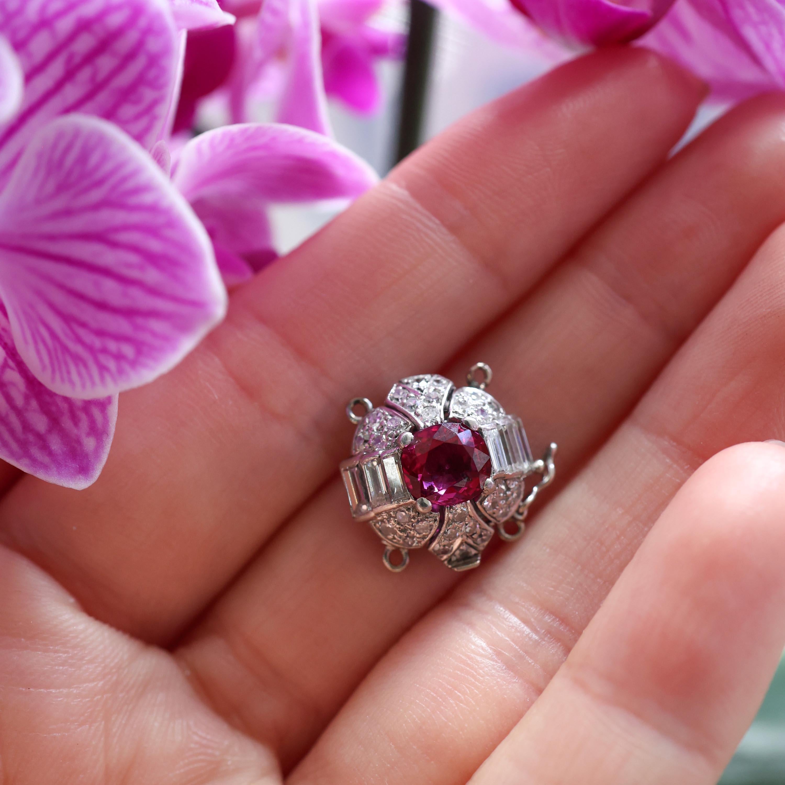 Eine Art Deco Rubin-, Diamant- und Platinschließe, mit einem ovalen, facettierten Burma-Rubin in der Mitte, mit einer diamantbesetzten Einfassung, bestehend aus drei Diamanten im Baguetteschliff, in Kanalfassungen, oberhalb und unterhalb des Rubins,