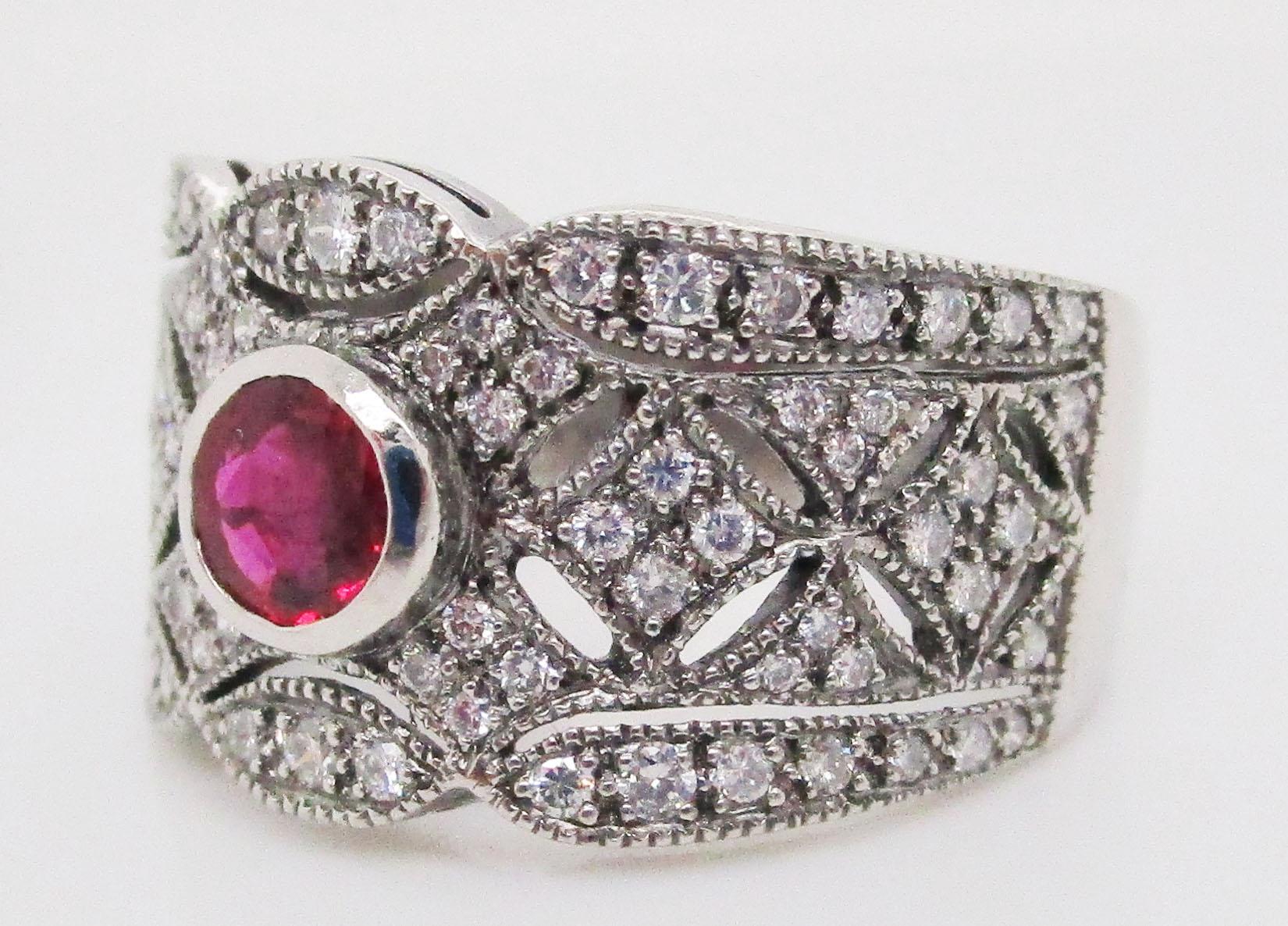 This absolutely stunning Art Deco Style band features gorgeous platinum filigree set with diamonds and boasting a rich red natural colored ruby center! The deep red hues of the natural colored ruby are nothing less than striking when set against the