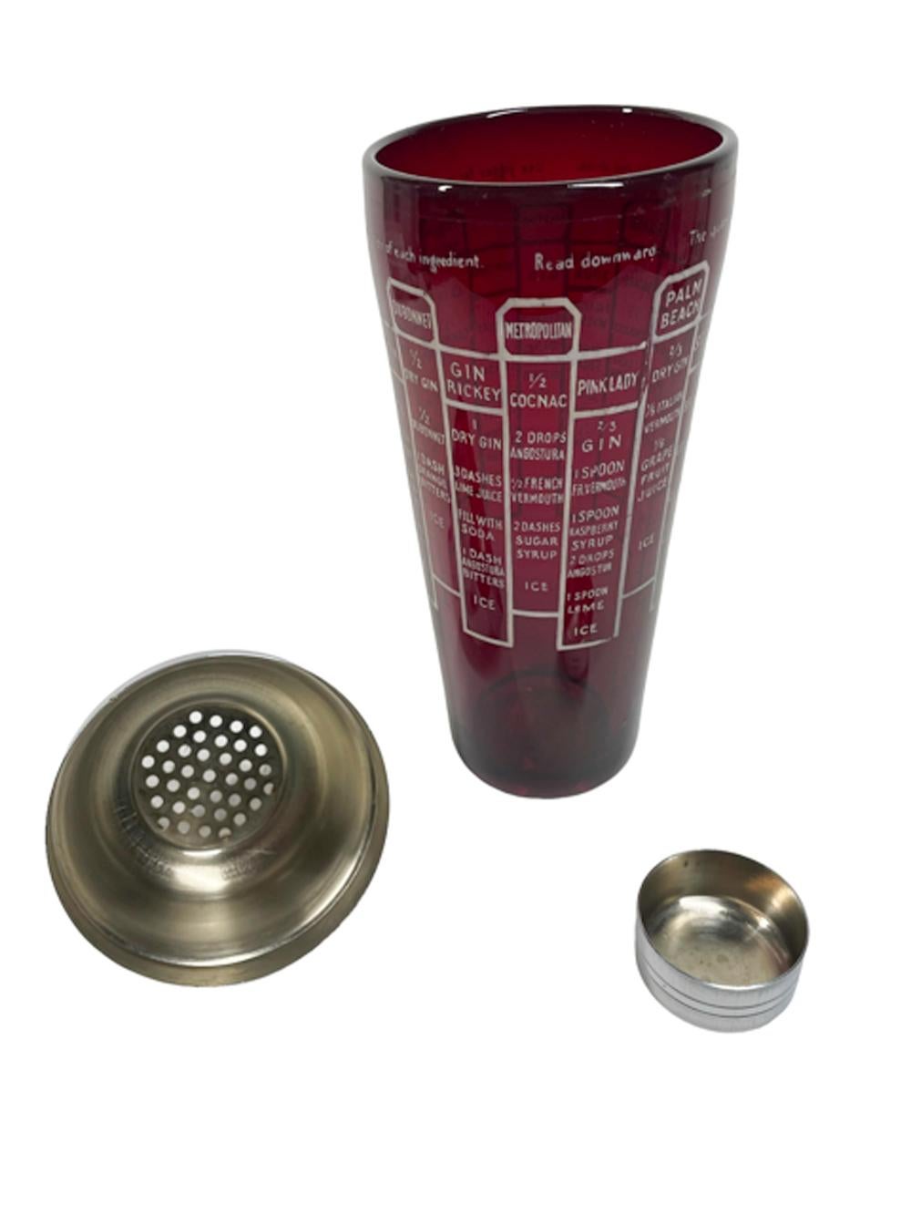 Art Deco ruby glass cocktail shaker with recipes for 16 cocktails in white graphics and with a chrome lid with integral strainer.