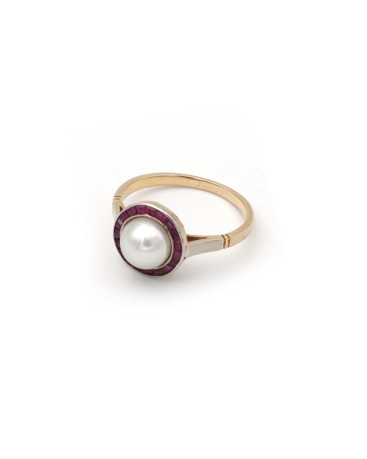 Anello Art Deco con rubino e perla a raggiera in oro 18 carati e platino. Di forma circolare, l'anello è centrato da una perla coltivata di 7 mm in un contorno di rubini calibrati (sintetici). La lucentezza della perla è molto brillante e vivida. Le