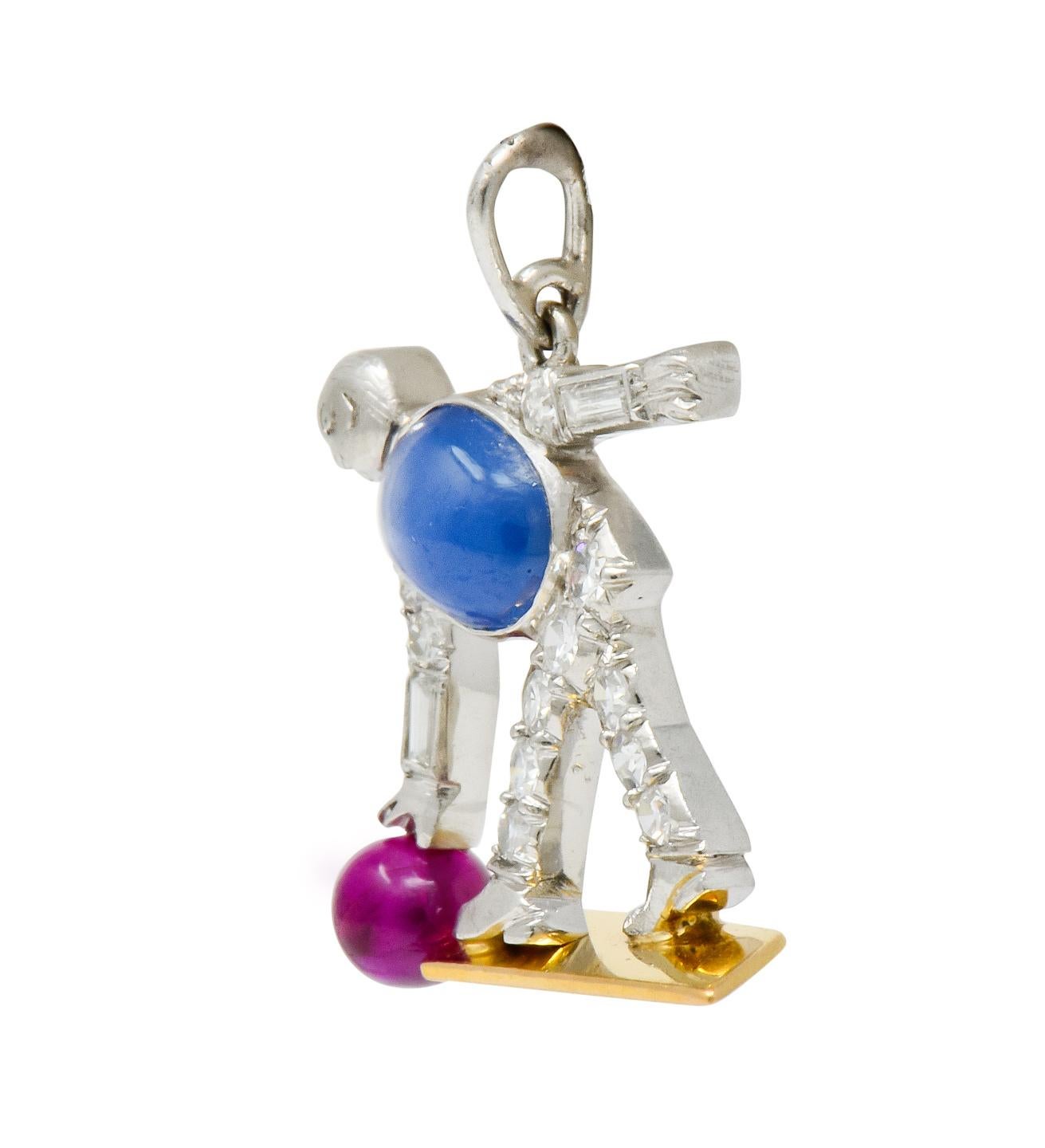 Designed as a bent over man about to release a ruby bead bowling ball down an 18 karat gold lane

Torso is comprised of a bezel set oval star sapphire cabochon; translucent and light blue in color with moderately strong six rayed star

Accented