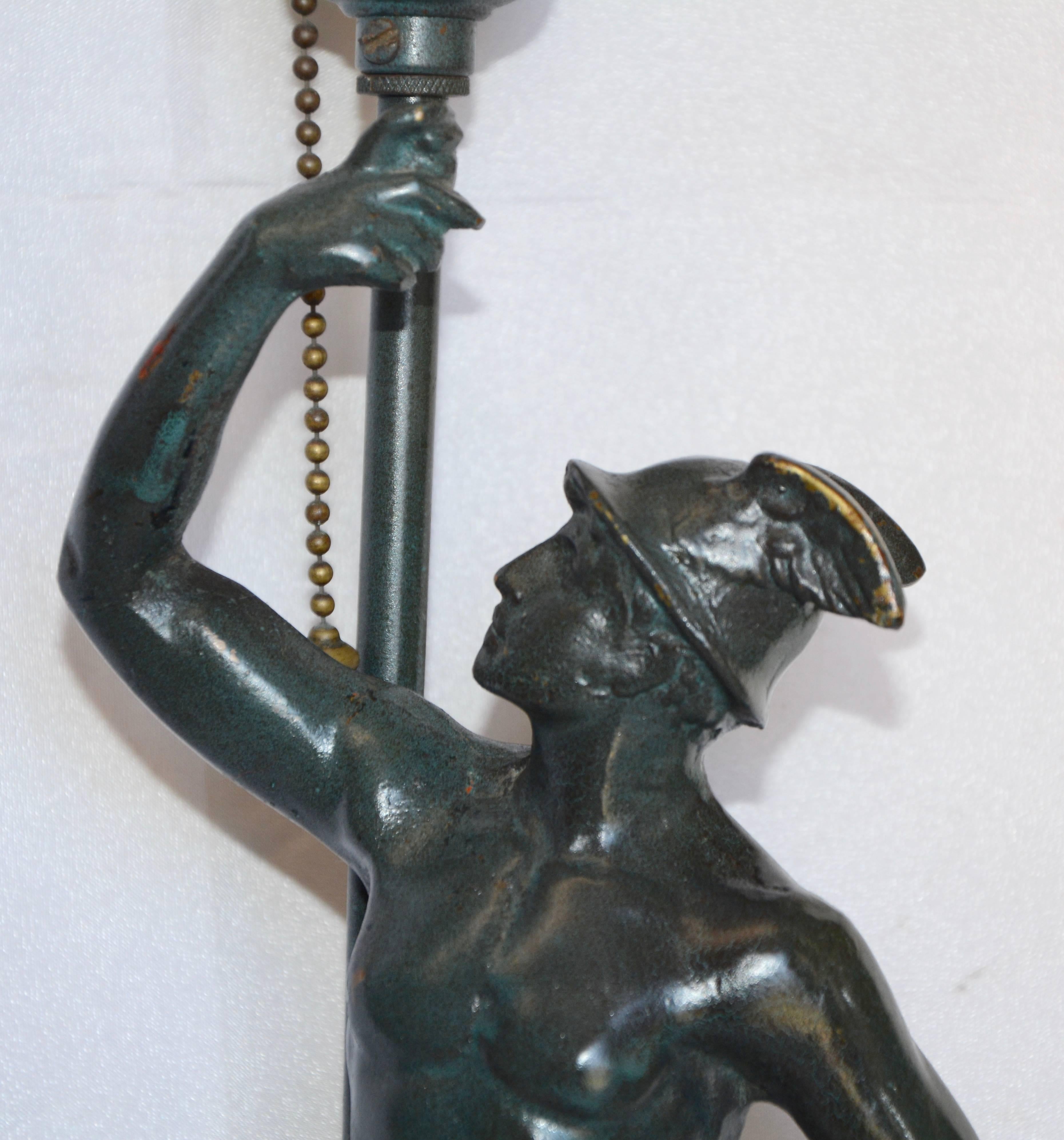 This Art Deco Mercury man is running with his flame in the form of a lamp socket with a satin glass flame shade. He is made of brass and has been painted a deep green. The ornate cast iron base has also been painted. The socket works and is operated