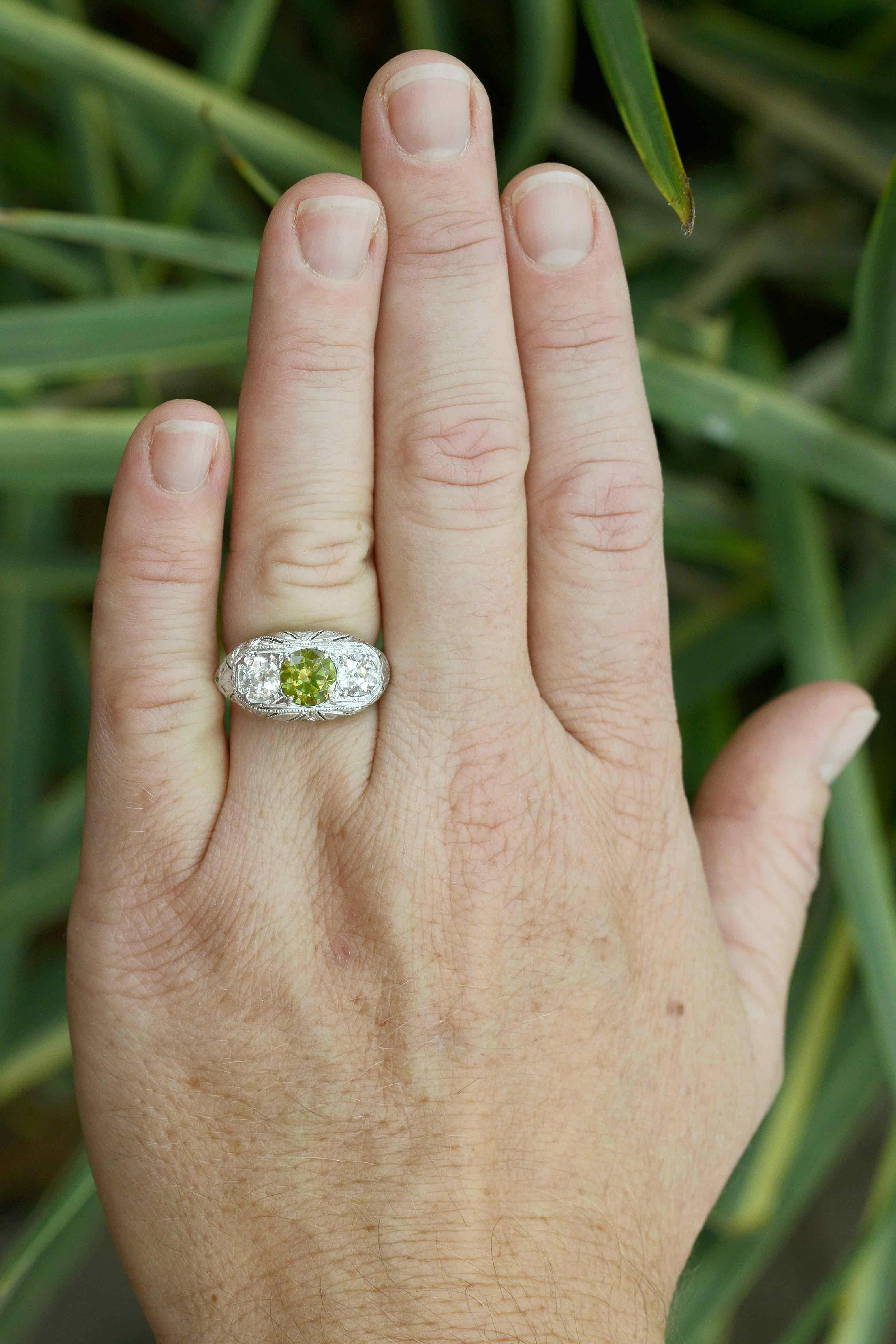 An alluring, exotic Art Deco Russian demantoid garnet and diamond three stone engagement ring. Rare, green garnets are seldom found in this size. At 1.50 carats and with a lush, vivid olive green, enticingly set between a pair of chunky, sparkling