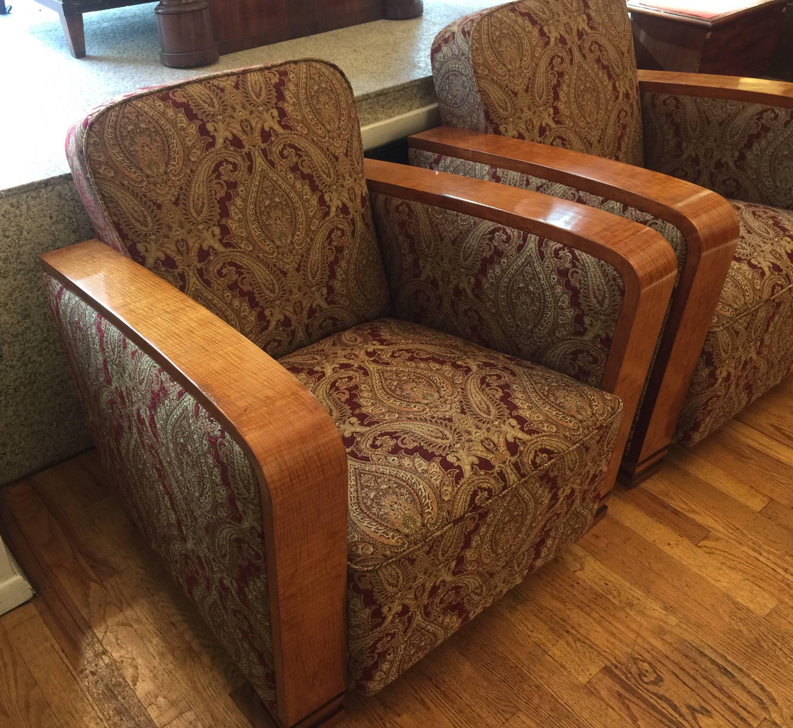 Recently reupholstered in a rich, antiqued, paisley-patterned fabric, the deep and generously sized chairs invite long hours of reading, conversation and rest. The solid, splayed wood of the arms and stylized, carved feet is thought to be African