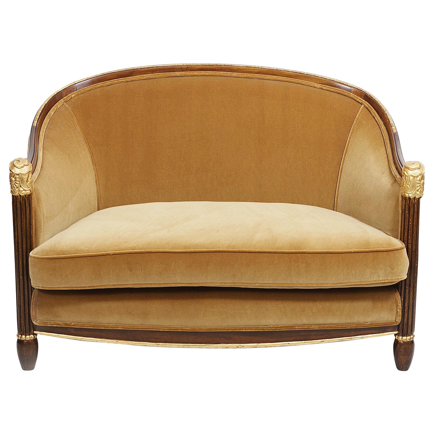 Extremely elegant French Art Deco carved salon settee covered in a rich gold velvet with front legs carved in gadroon style, finished at top in a hand carved floral pattern decorated in gold leaf. Top section of the bowed back is carved in a series