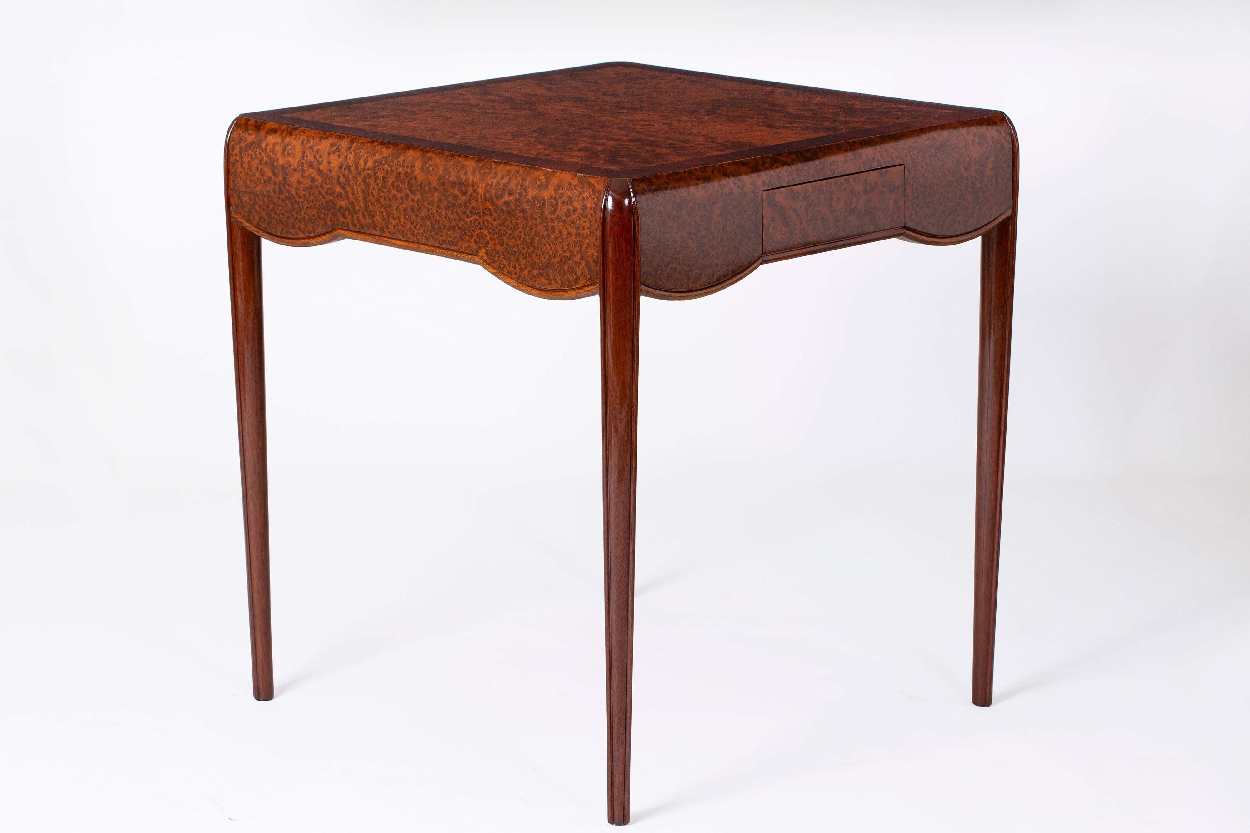 Extremely elegant Art Deco salon table by Lucie Renaudot manufactured in a beautiful cut of amboyna burl and mahogany wood from circa 1927. The top section, which sits on four graceful tapering legs, has a pair of frieze drawers which makes it ideal