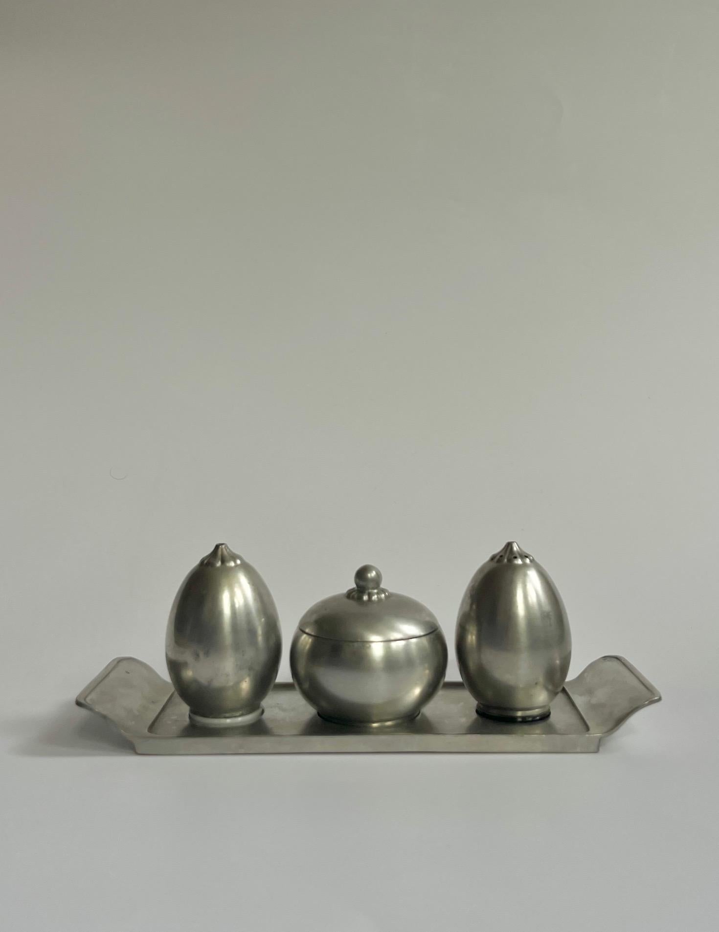 Ein schönes Service aus den 1940er Jahren von Just Andersen. Seltenes, vollständig intaktes und originales Set mit Tablett, Salz- und Pfefferstreuern und einer Zucker- und Gewürzdose mit Deckel. Alle Shaker sind aus Zinn und haben ihre originalen