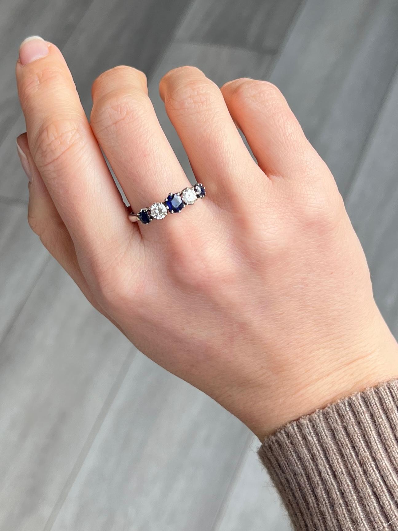 Dieser wunderschöne Ring enthält drei tiefblaue Saphire und zwei Diamanten von je 30 Pence. Der zentrale Saphir misst 40pt und die kleineren an der Außenseite des Rings messen jeweils 20pts. Der Ring ist aus 18 Karat Weißgold gefertigt. 

Ringgröße: