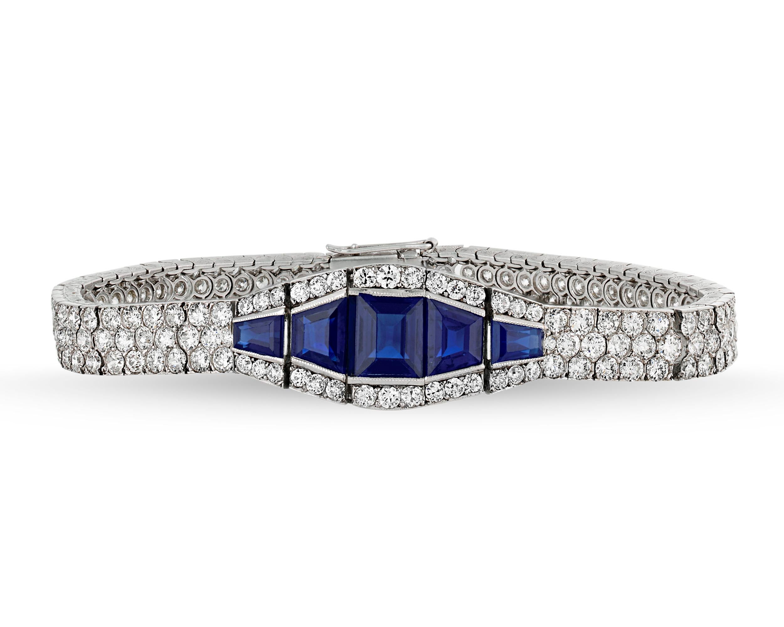 This spectacular sapphire bracelet embodies the sleek and stylish spirit of Art Deco design. The bracelet is embedded with a bold geometric design of white diamonds totaling approximately 16.00 carats, while rich, royal blue sapphires totaling