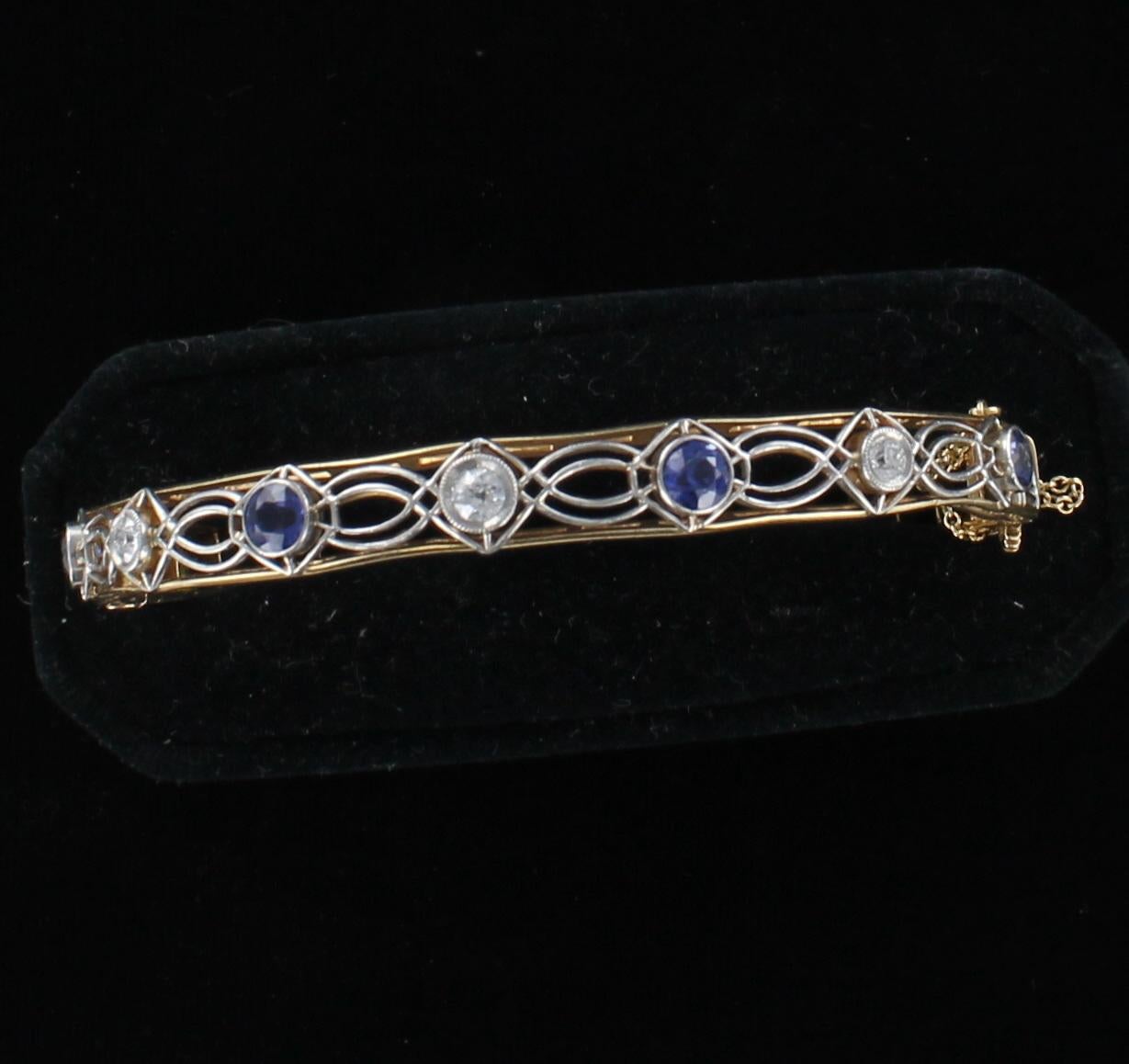 This openwork yellow gold and platinum bracelet is an heirloom treasure.  Four sapphires and three diamonds are bezel-set and alternate across the top of the bangle.  This lovely Art Deco bracelet is representative of the beauty and artisanship of