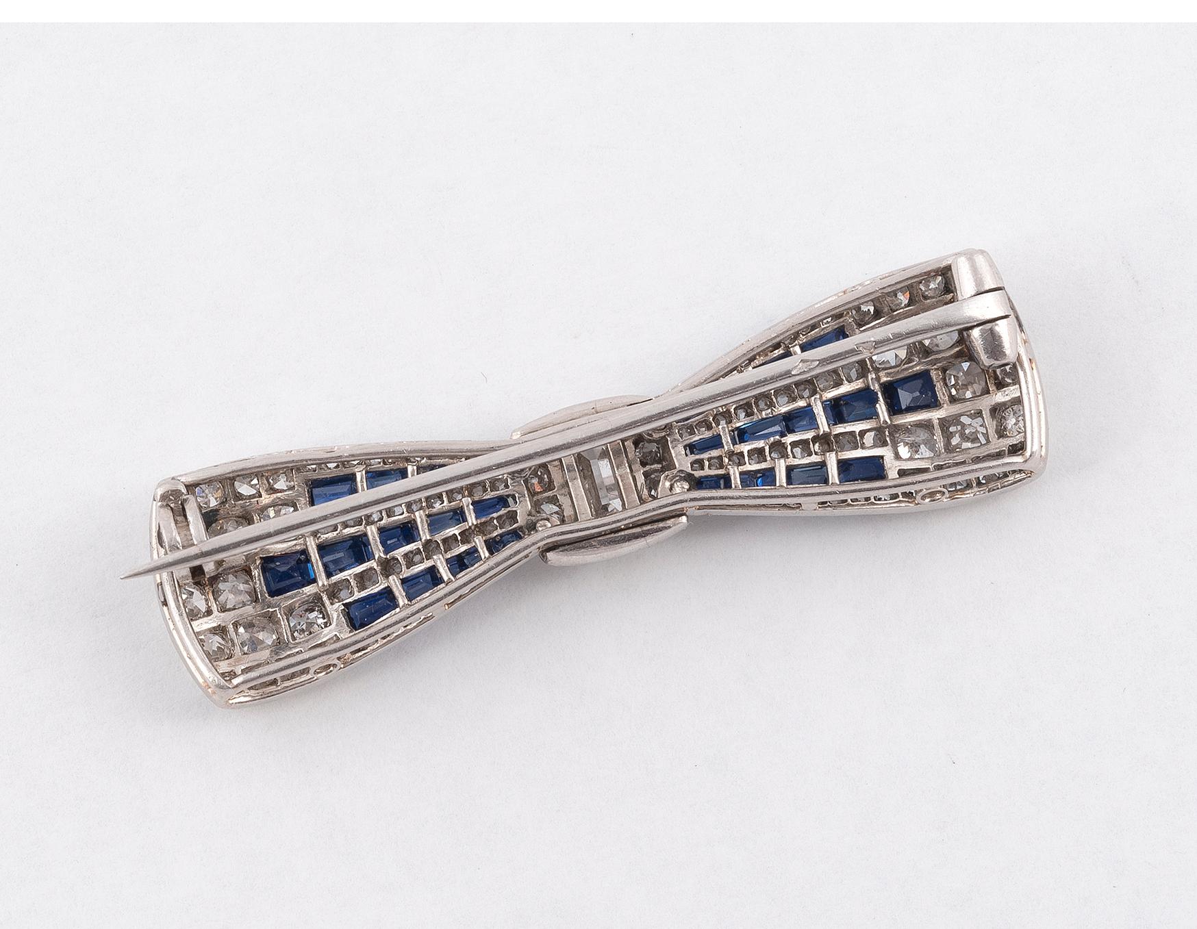 The tied ribbon bow, set throughout millegrain-set with single-cut diamonds, calibre' sapphire, the central baguette-cut diamond approximately 0,70ct, signed Boucheron, French assay marks,
Mounted in platinum
Length 4.1cm.
