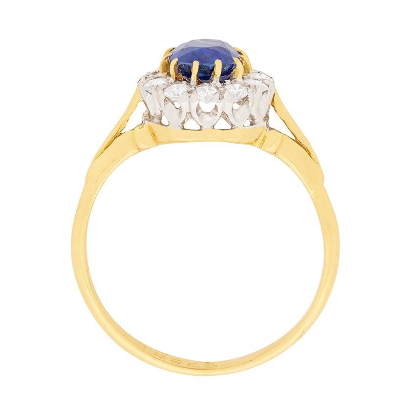 This ring features a cornflower blue sapphire surrounded by a halo of diamonds. The natural sapphire is oval shaped and weighs 1.25 carat. It is claw set using 18 carat yellow gold, whilst the surrounding halo of diamonds is set within platinum. The