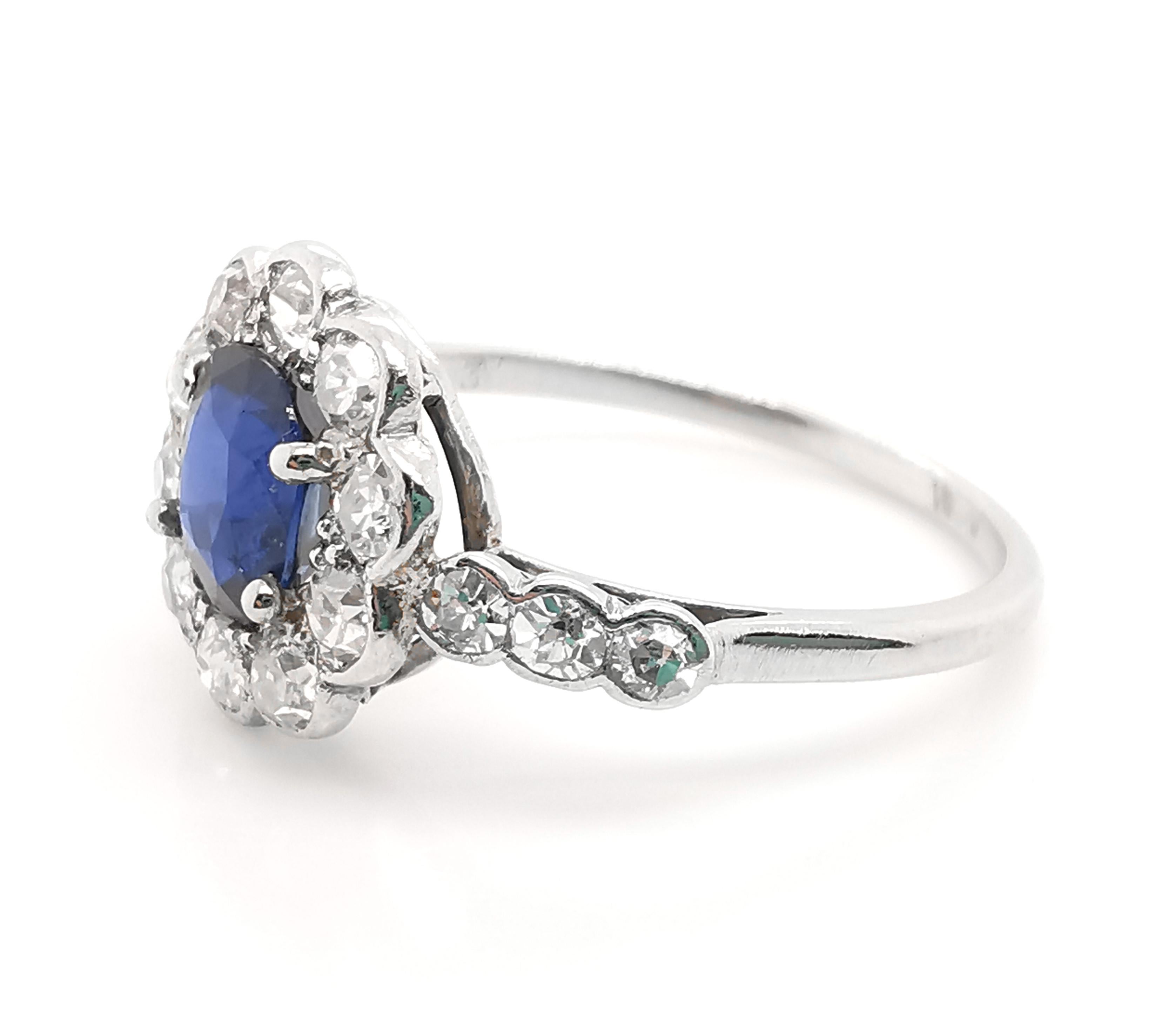 A sapphire and diamond cluster ring, with an oval, faceted sapphire, weighing approximately 1.03ct, in a four claw setting, with a surrounding cluster, set with ten, old-cut diamonds, in half rub over, half grain settings, with three eight-cut