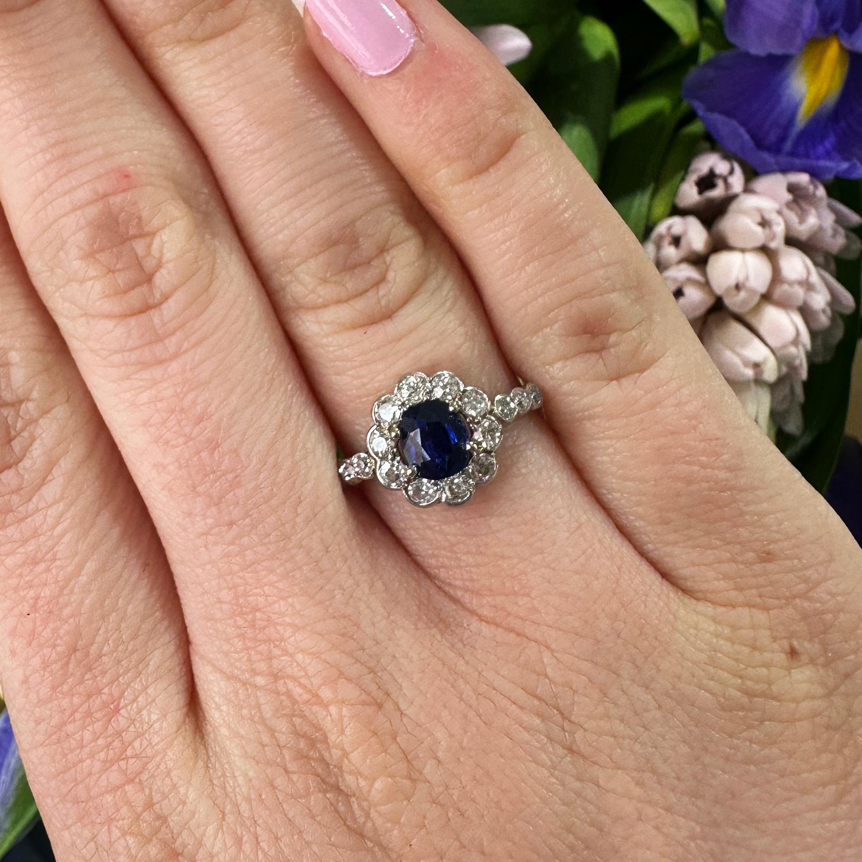 A sapphire and diamond cluster ring, with an oval, faceted sapphire, weighing approximately 1.03ct, in a four claw setting, with a surrounding cluster, set with ten, old-cut diamonds, in half rub over, half grain settings, with three eight-cut