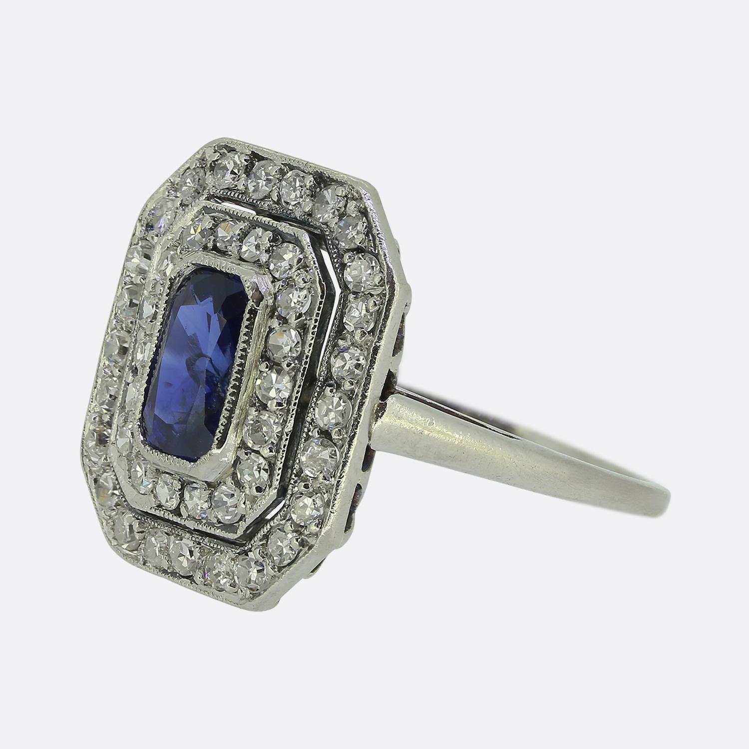 Hier haben wir einen bezaubernden Art-Déco-Ring mit einem fesselnden, ovalen, facettierten blauen Saphir in der Mitte. Der prächtige Hauptstein sitzt leicht erhöht in einer feinen Millegrain-Fassung und ist von einer doppelten Fassung aus Diamanten