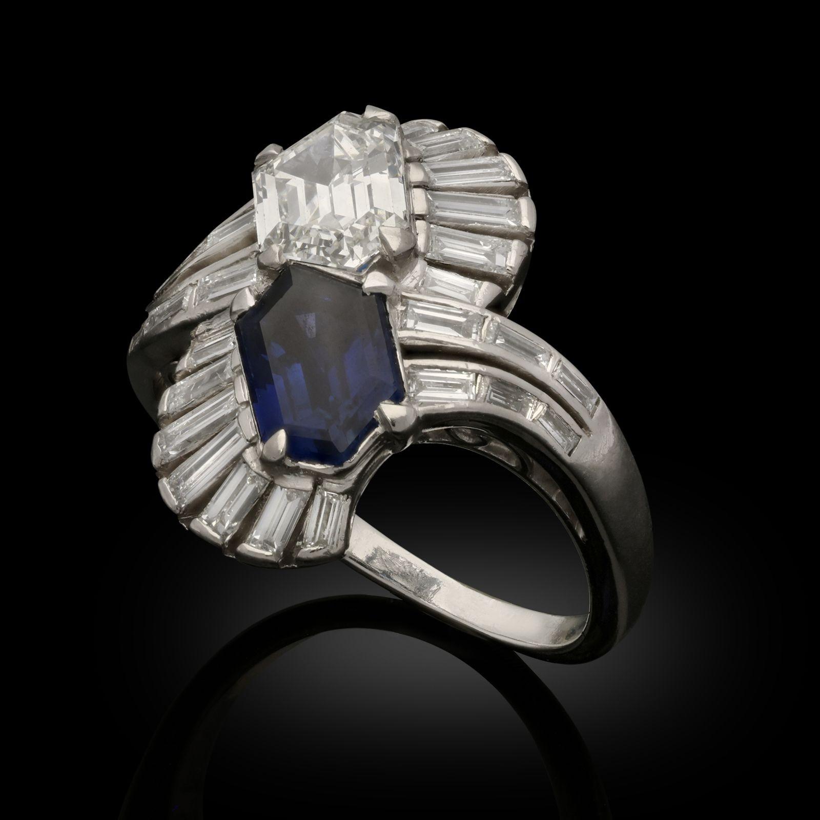 A beautiful Art Deco sapphire and diamond ring c.1930 designed as two stylised peacock feathers in a vertical cross over design, the ‘eyes’ of each feather formed of either a hexagonal step cut sapphire or diamond, above each is a fan shape of