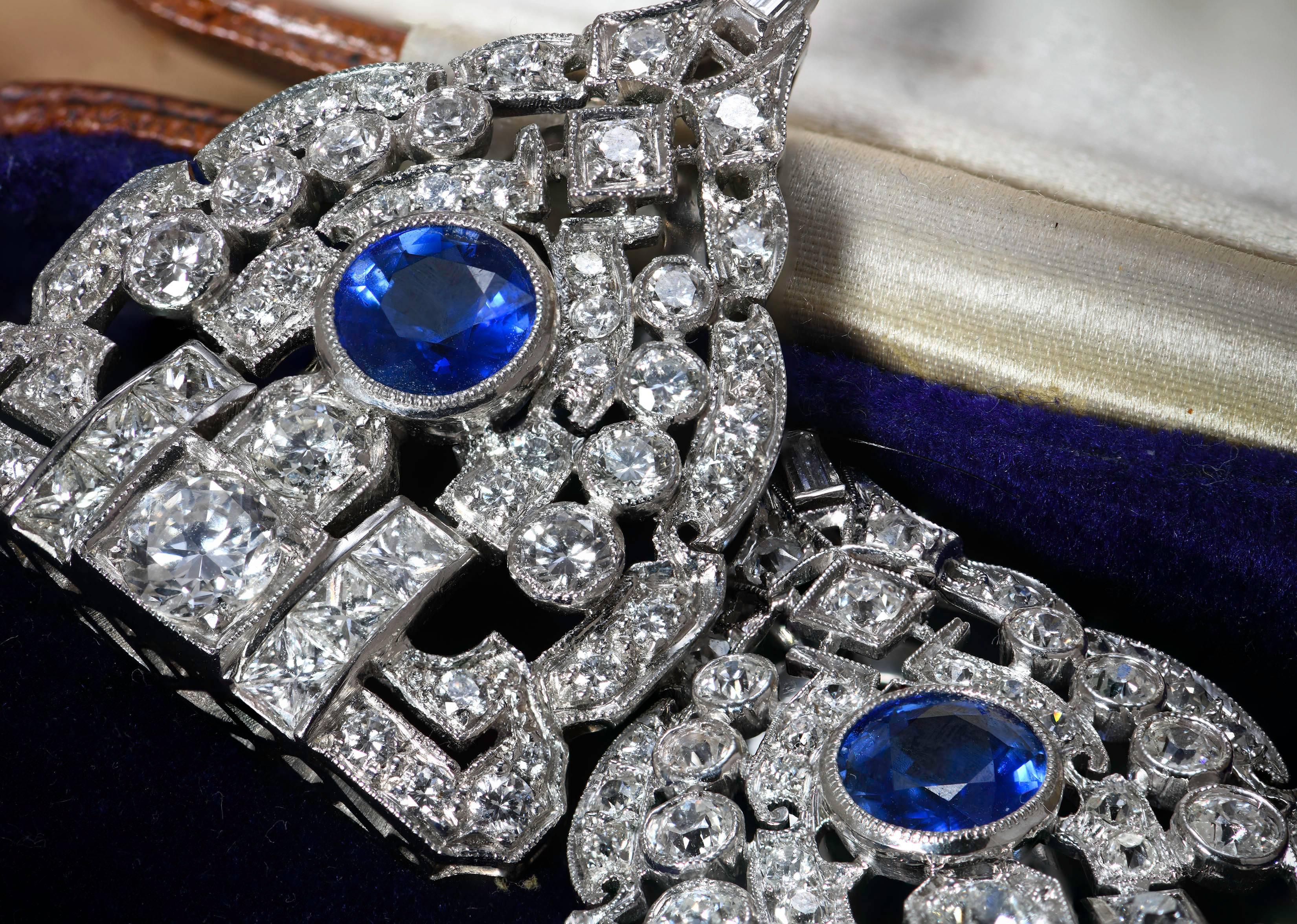 These are stunning sapphire and diamond double clips. Each is set with a round sapphire of about 1.6 carats and diamonds cut in a variety of styles. Most are brilliant cut with the largest of these at the centre of the straight edge。 Either side of