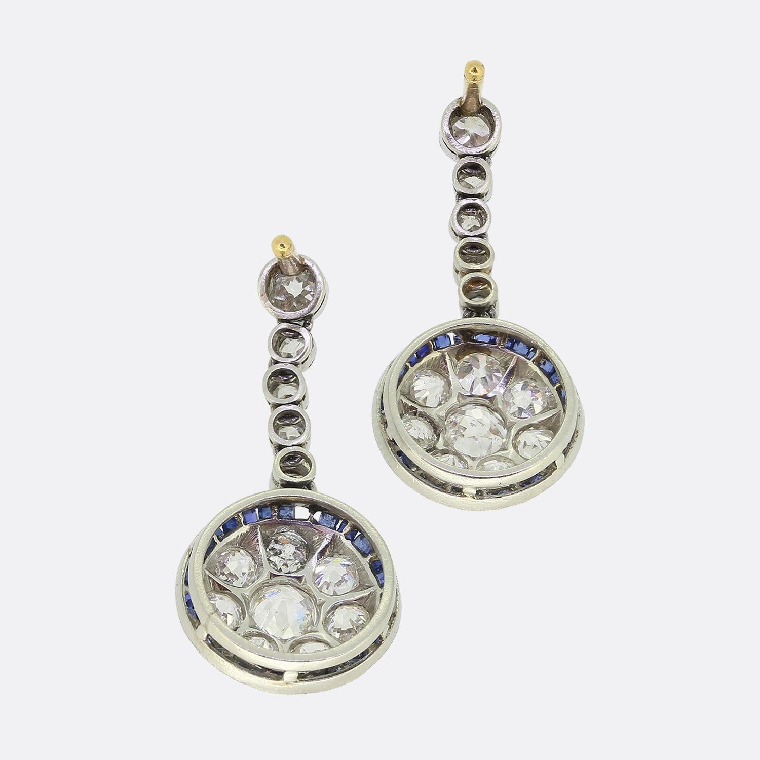 Here we have a delightful pair of drop earrings crafted at a time when the Art Deco style was at the forefront of design. Five individually milgrain set old cut diamonds play host to a circular target motif below. This clustered design consists of