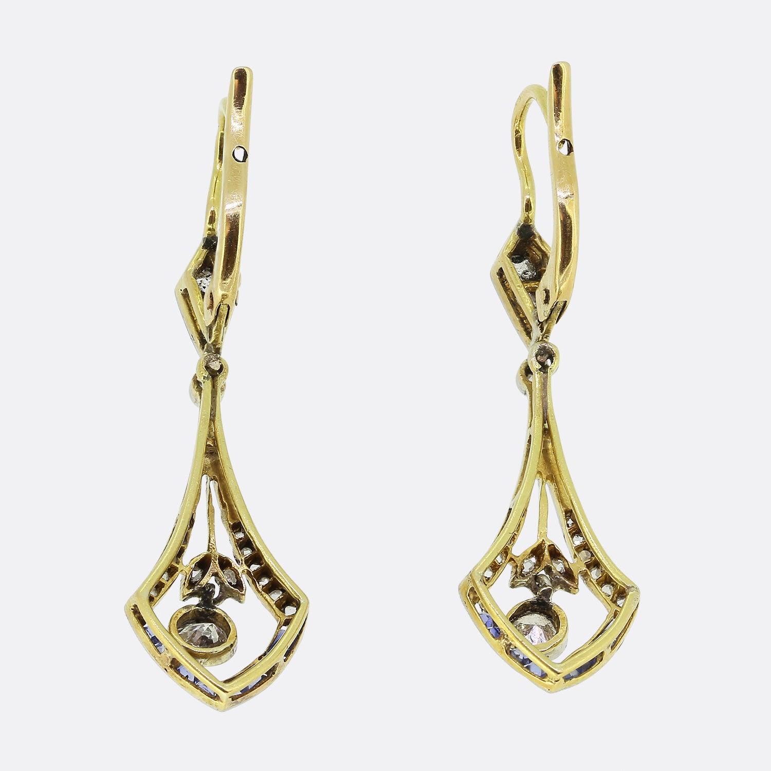 Here we have a charming pair of Art Deco drop earrings. Each earring features a moveable diamond drop that sits in the centre of a calibrated sapphire and diamond design. These earrings are a great example of art Deco style and are crafted in 18ct