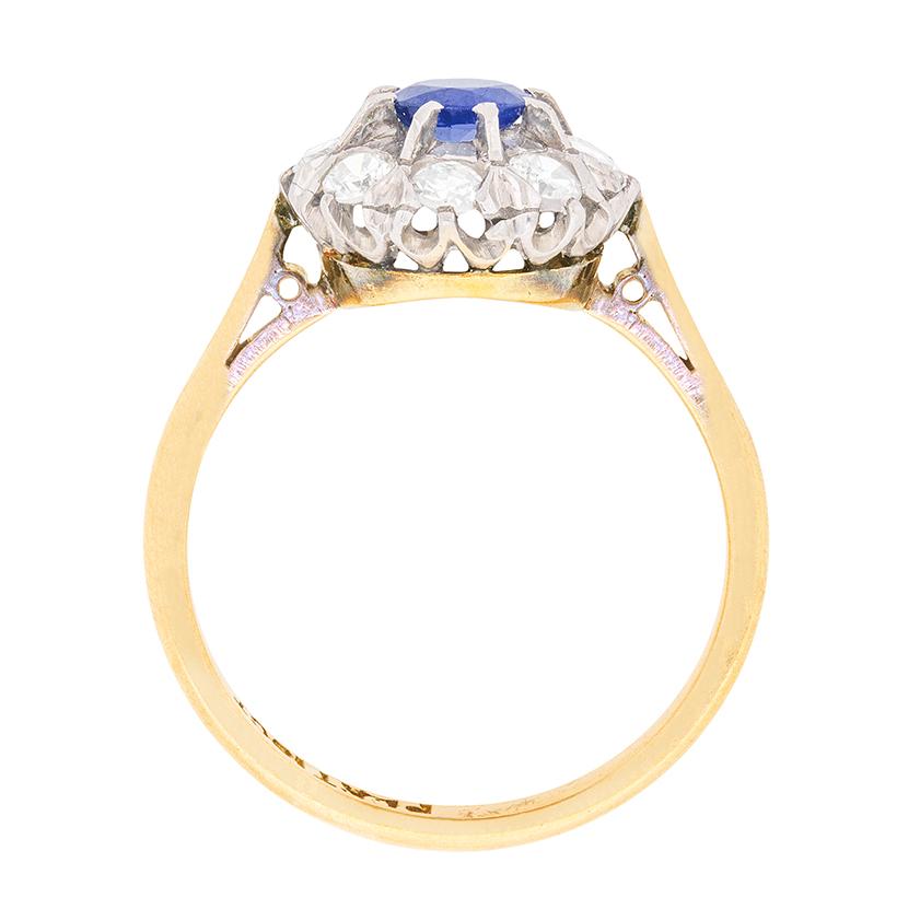 In the centre of this cluster ring is a royal blue sapphire weighing 0.40 carat. It is claw set and surrounded by dazzling diamonds. The diamonds are transitional cuts and have a combined weight of 0.40 carat. They are estimated as G in colour and